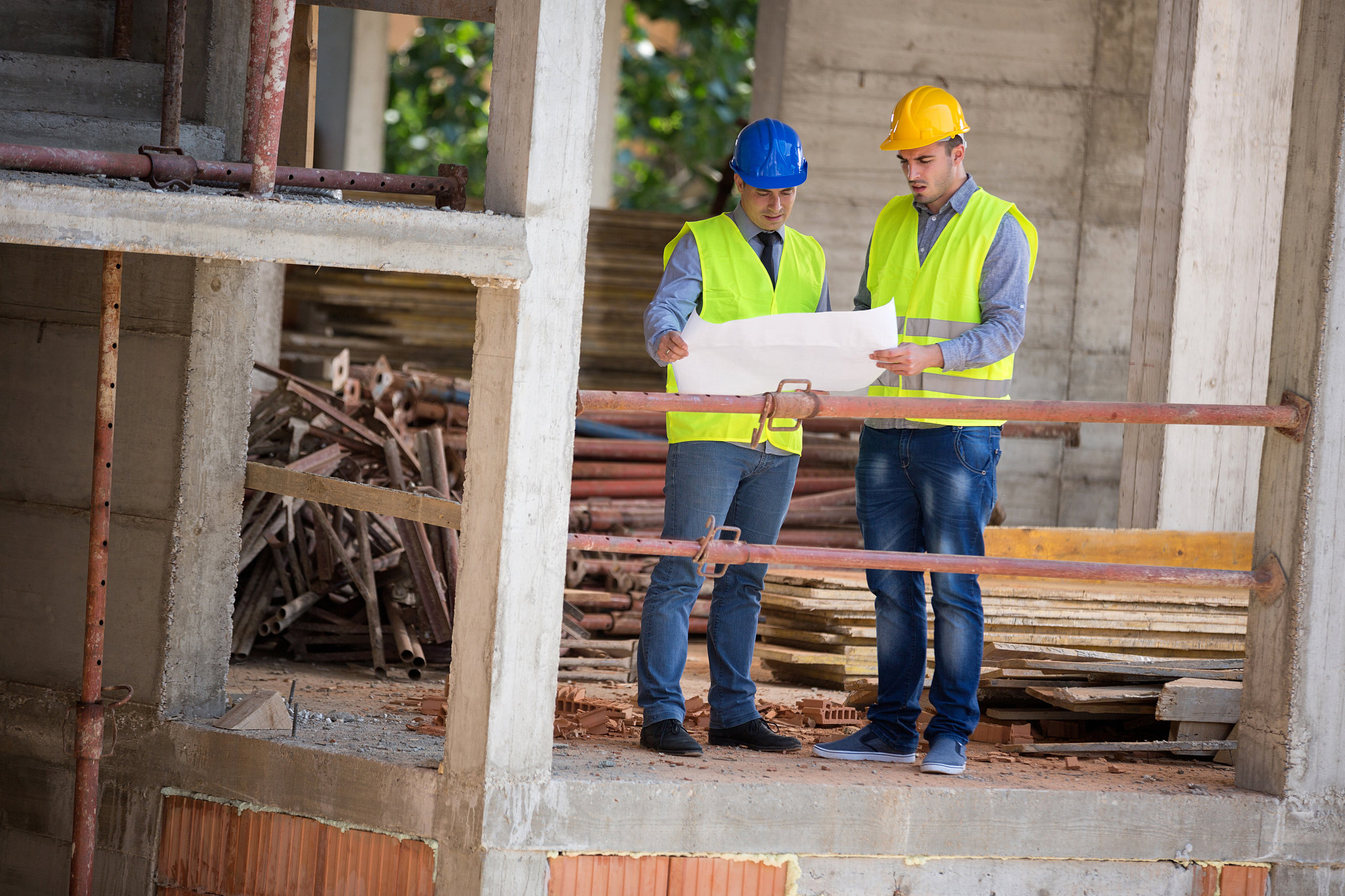 male architects look at blue print on building construction