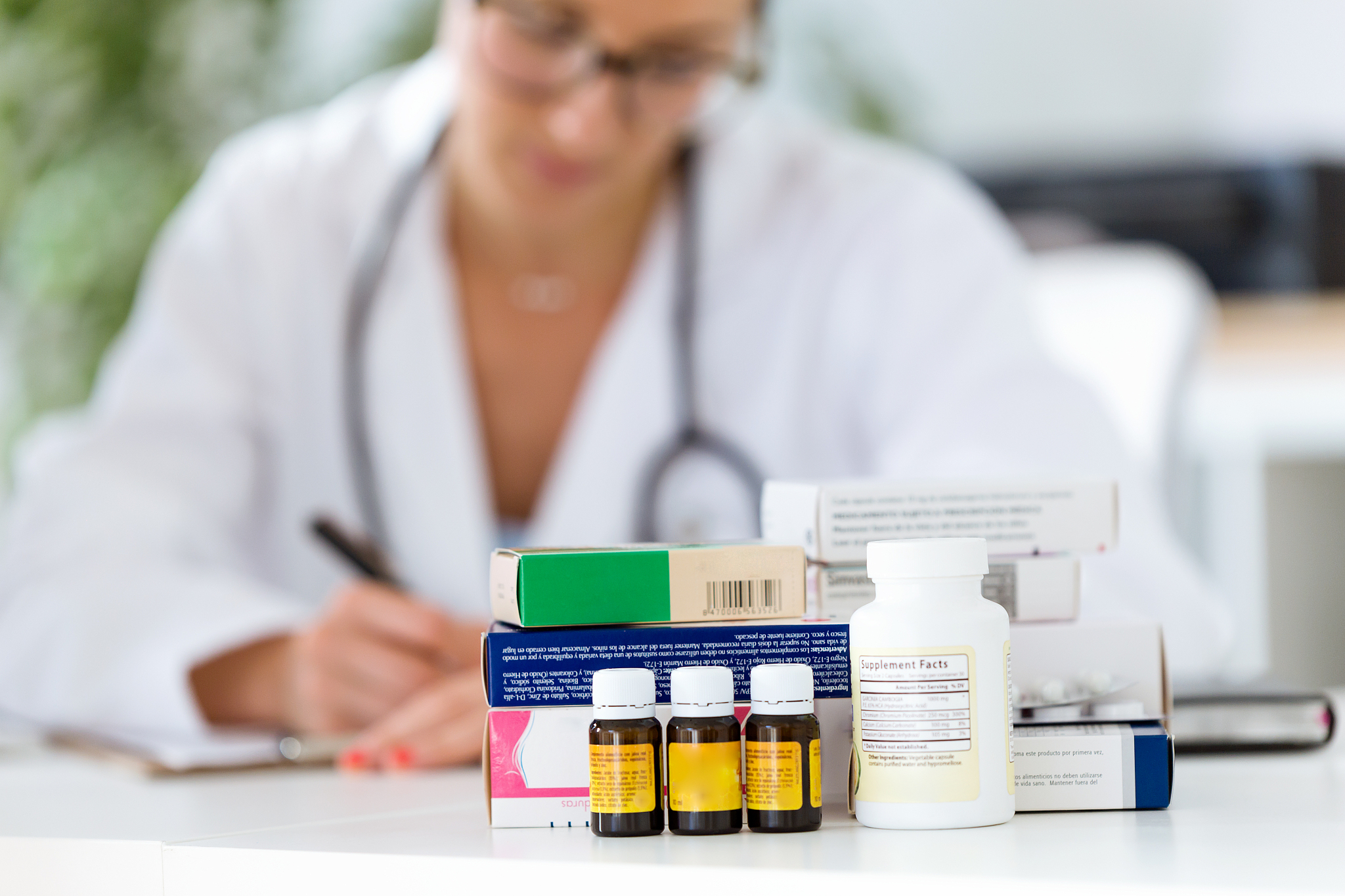 beautiful female pharmacist holding jar of pills in hands.