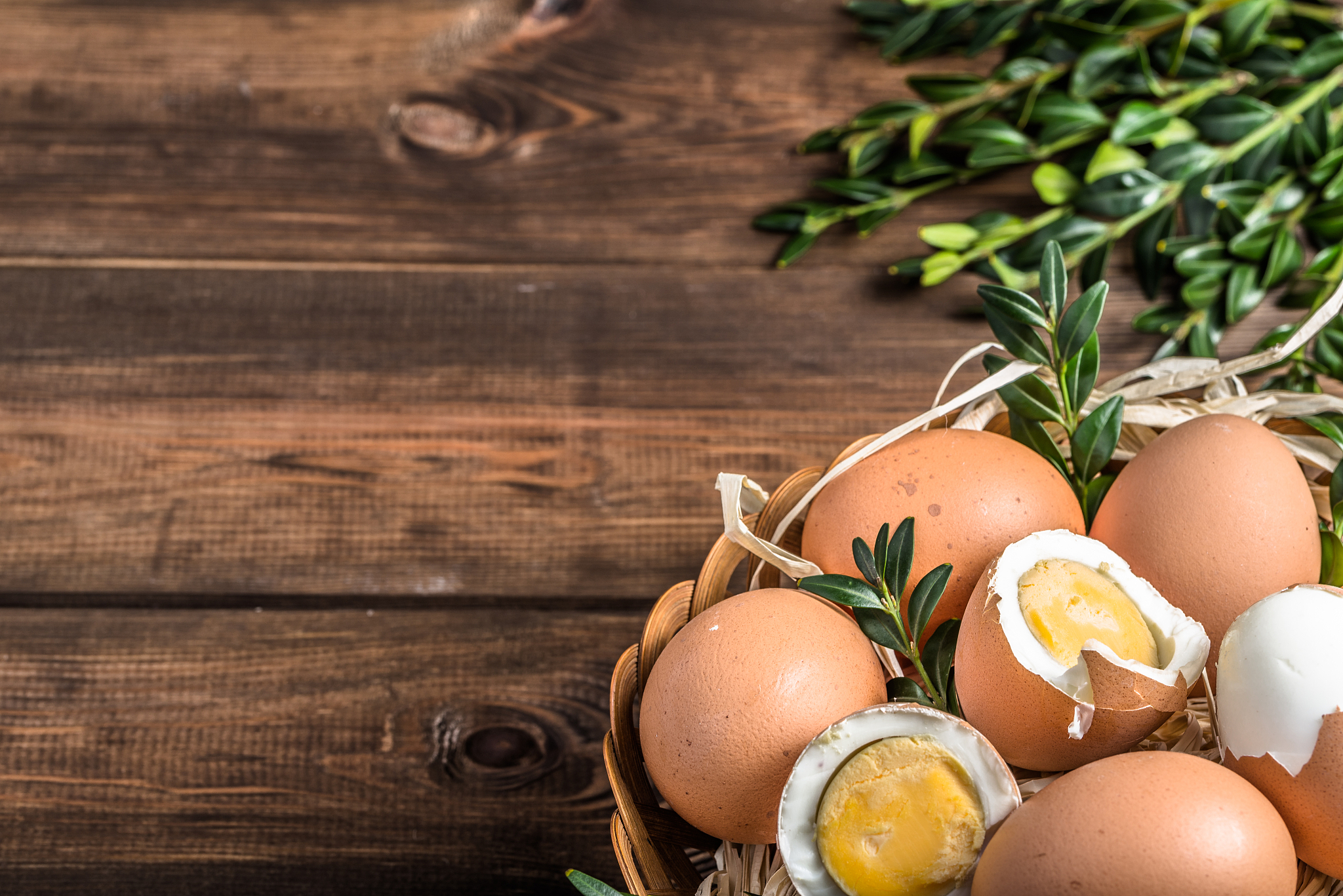 fresh farm eggs in the basket and hard boiled egg with yolk, top