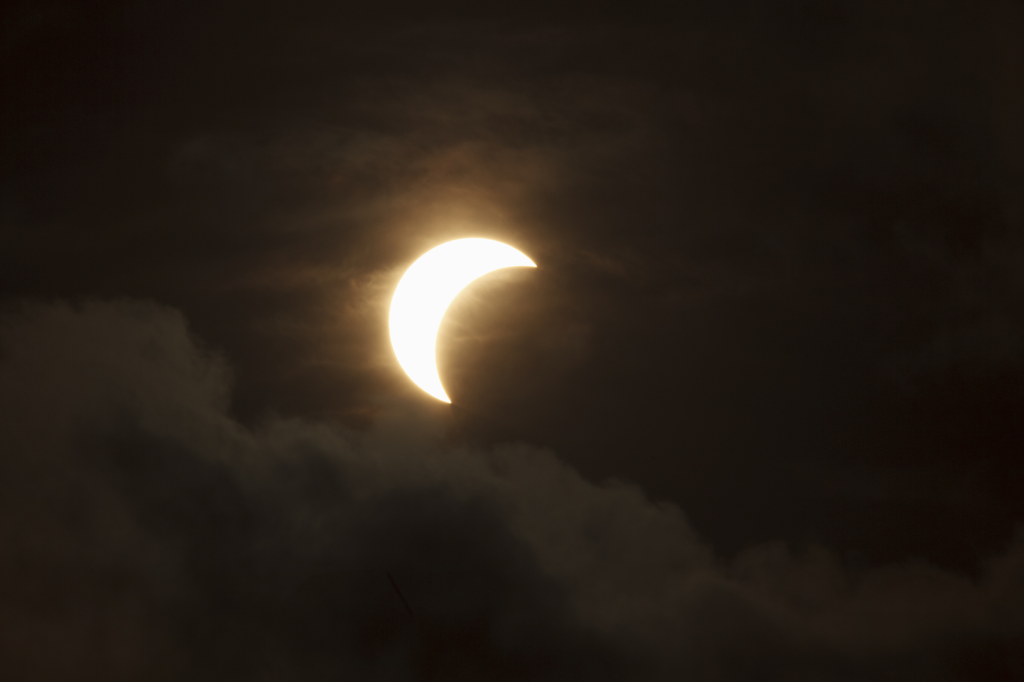partial solar eclipse through clouds
