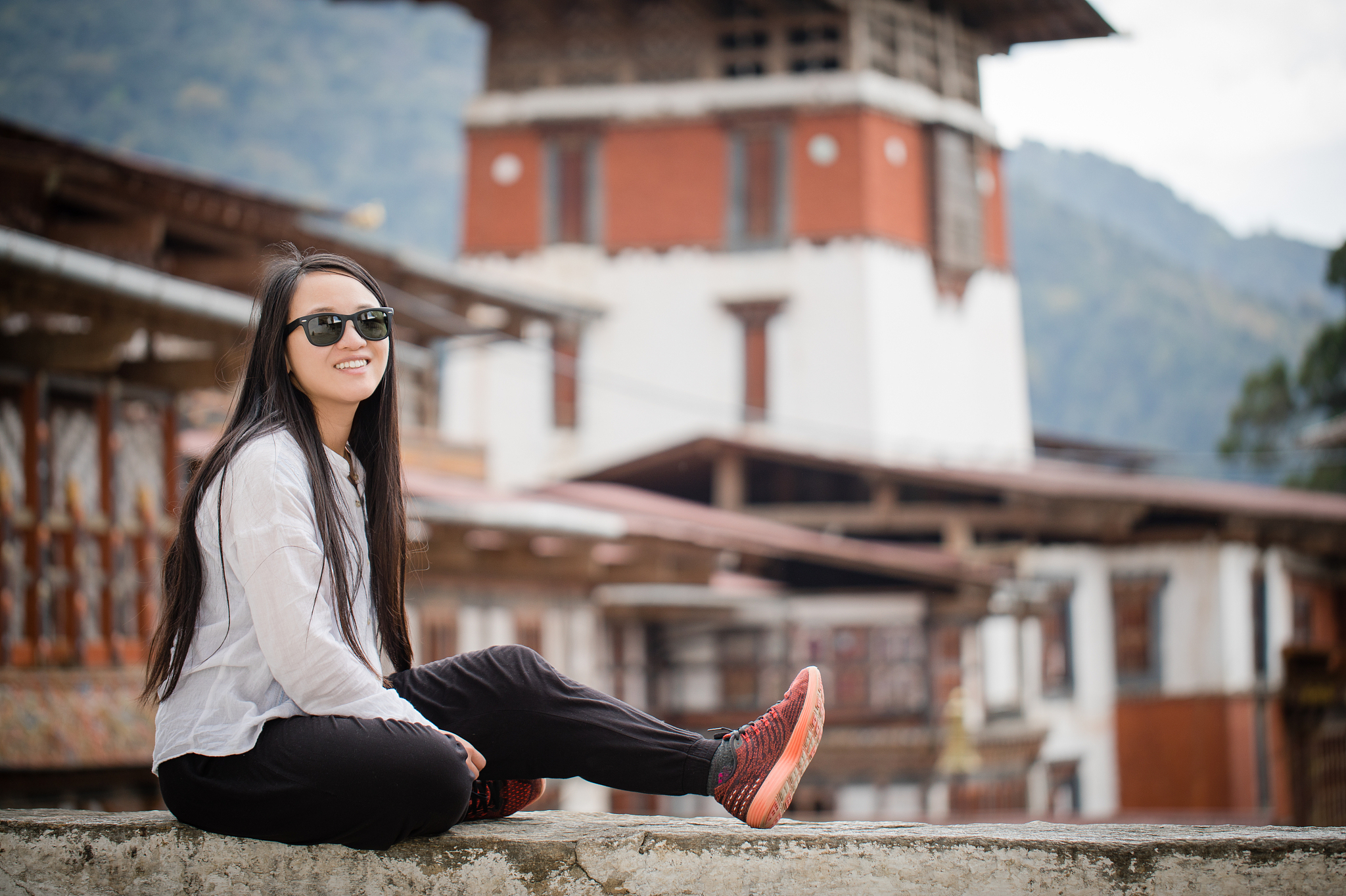 a young woman sitting by the ledge in trongsa, bhutan