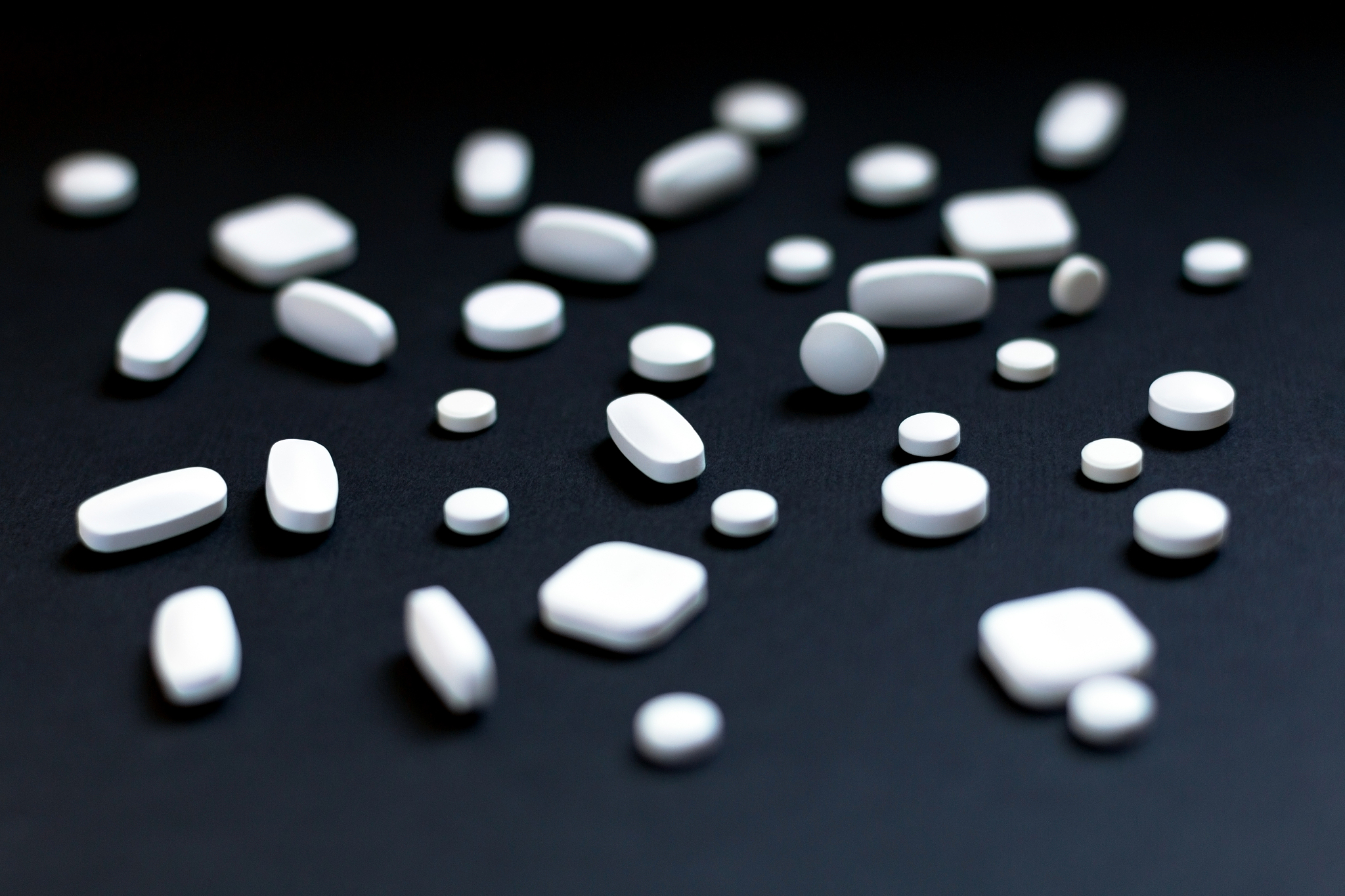 white pills on black paper background.