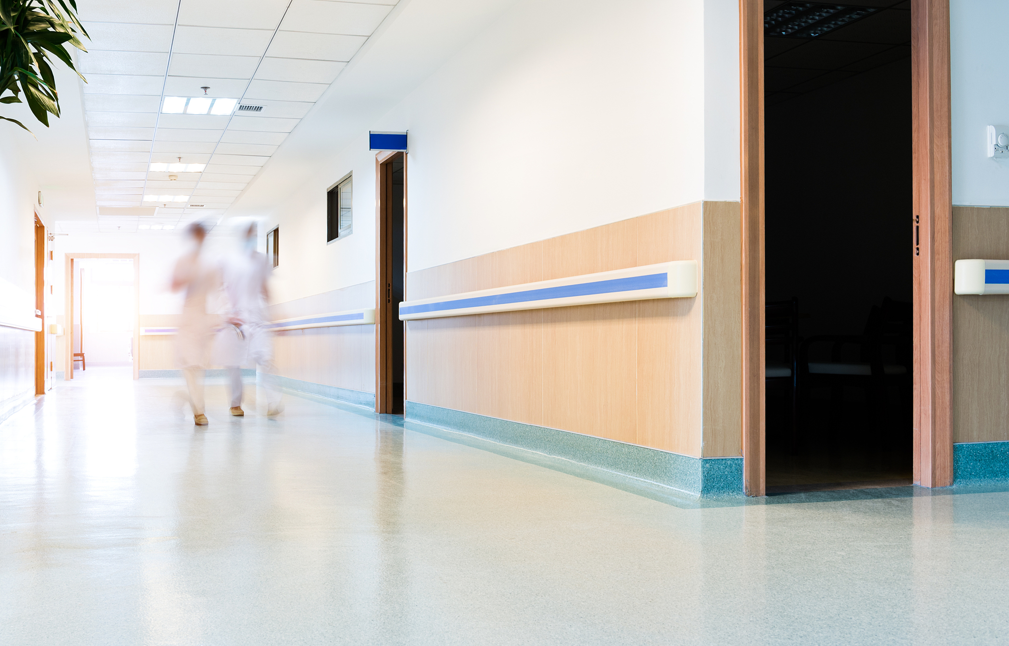 blurred figures wearing medical uniforms walking through the hal