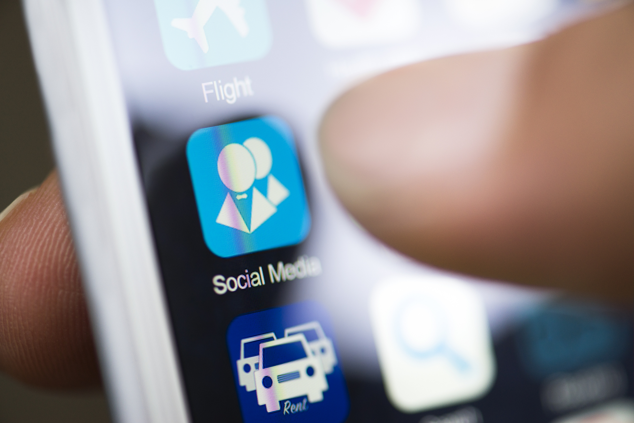 hand holding phone, social media app icon on screen