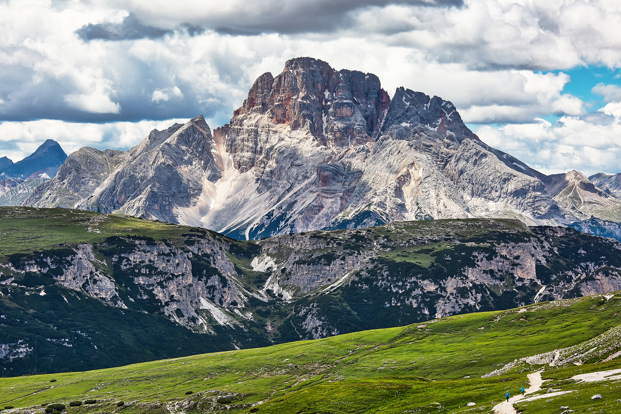 mountain landscape with green meadow and two people in the foreg