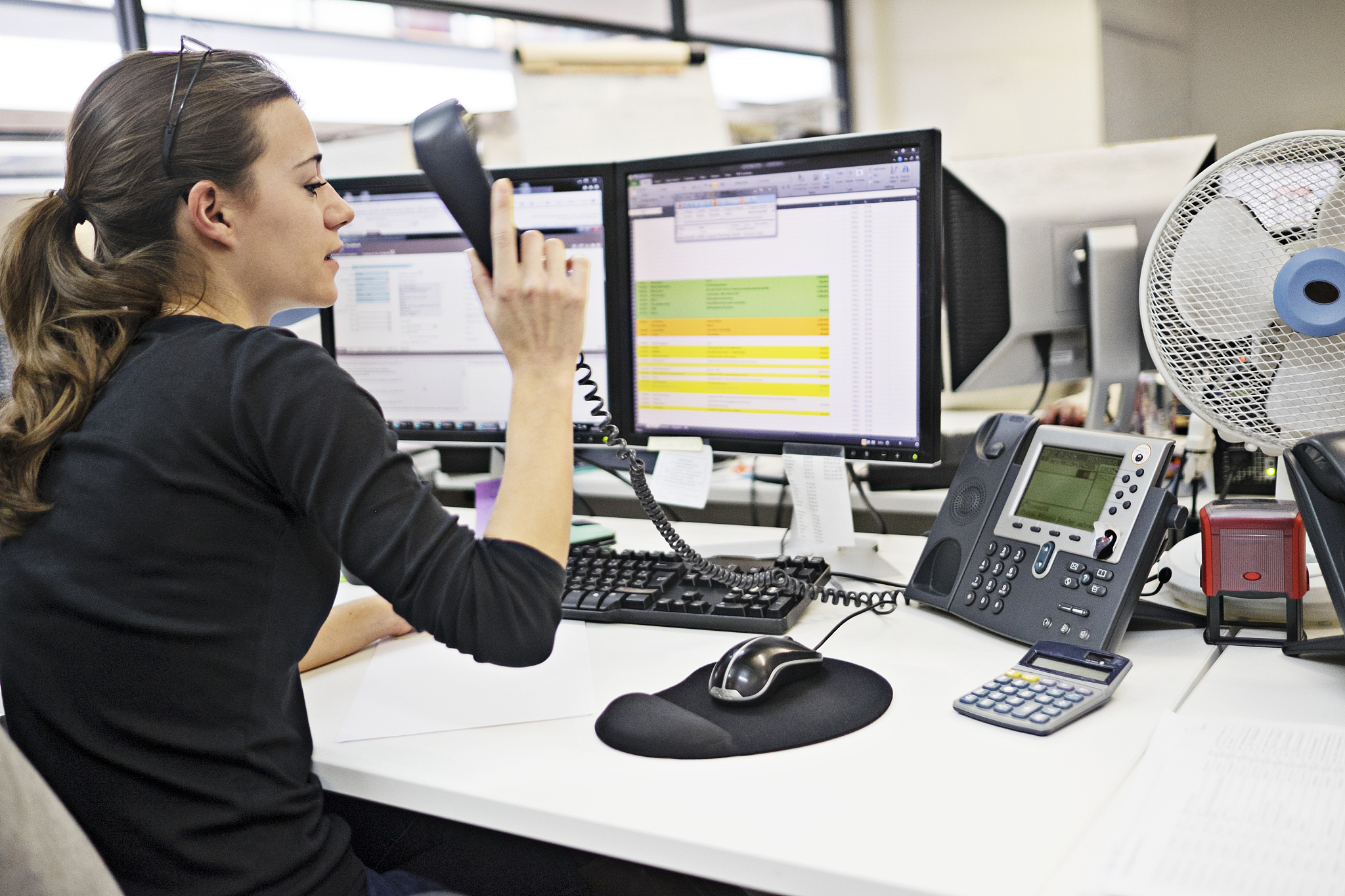 woman in office piking up the telephone