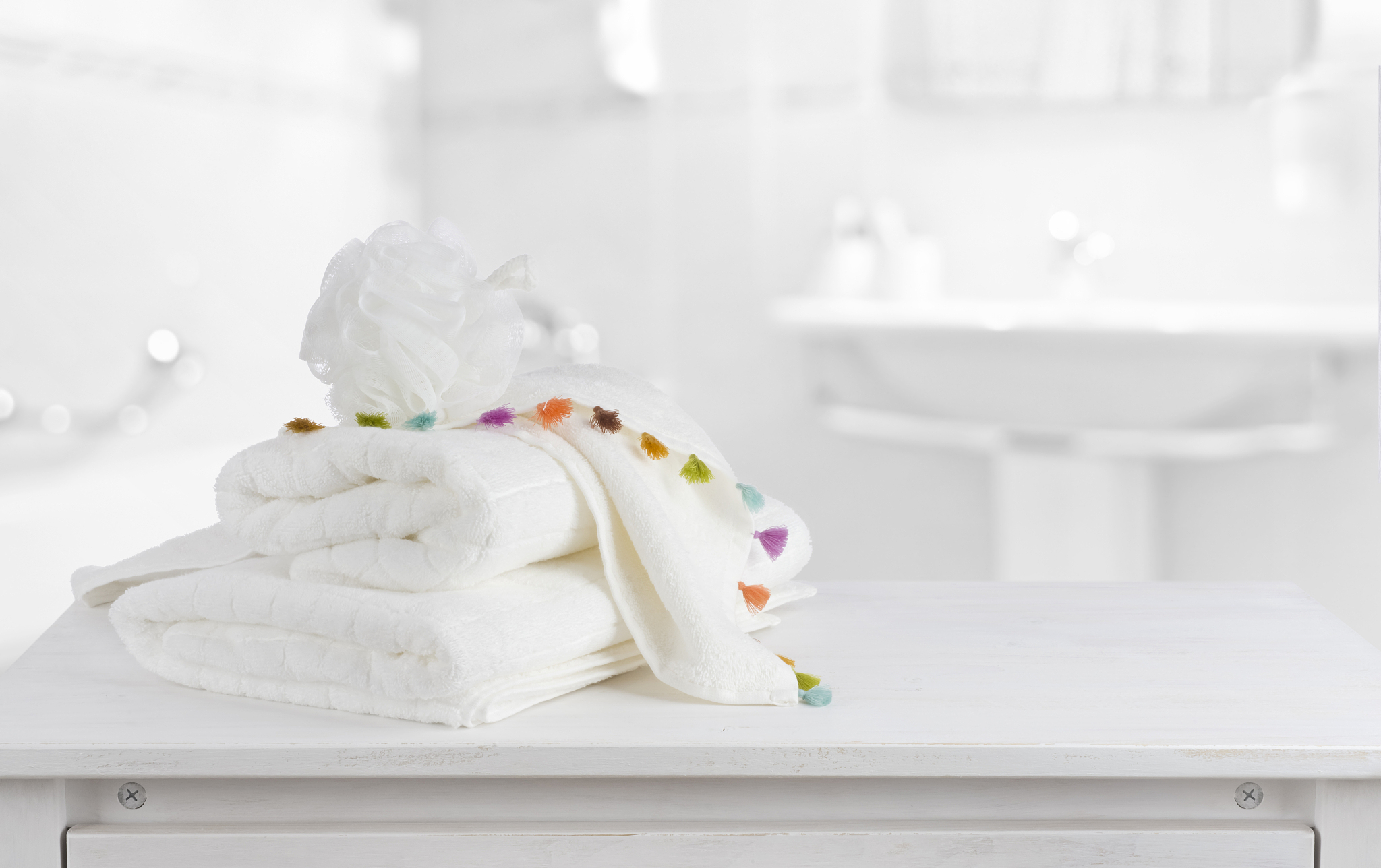 white cotton towels on wooden counter table inside bright bathro