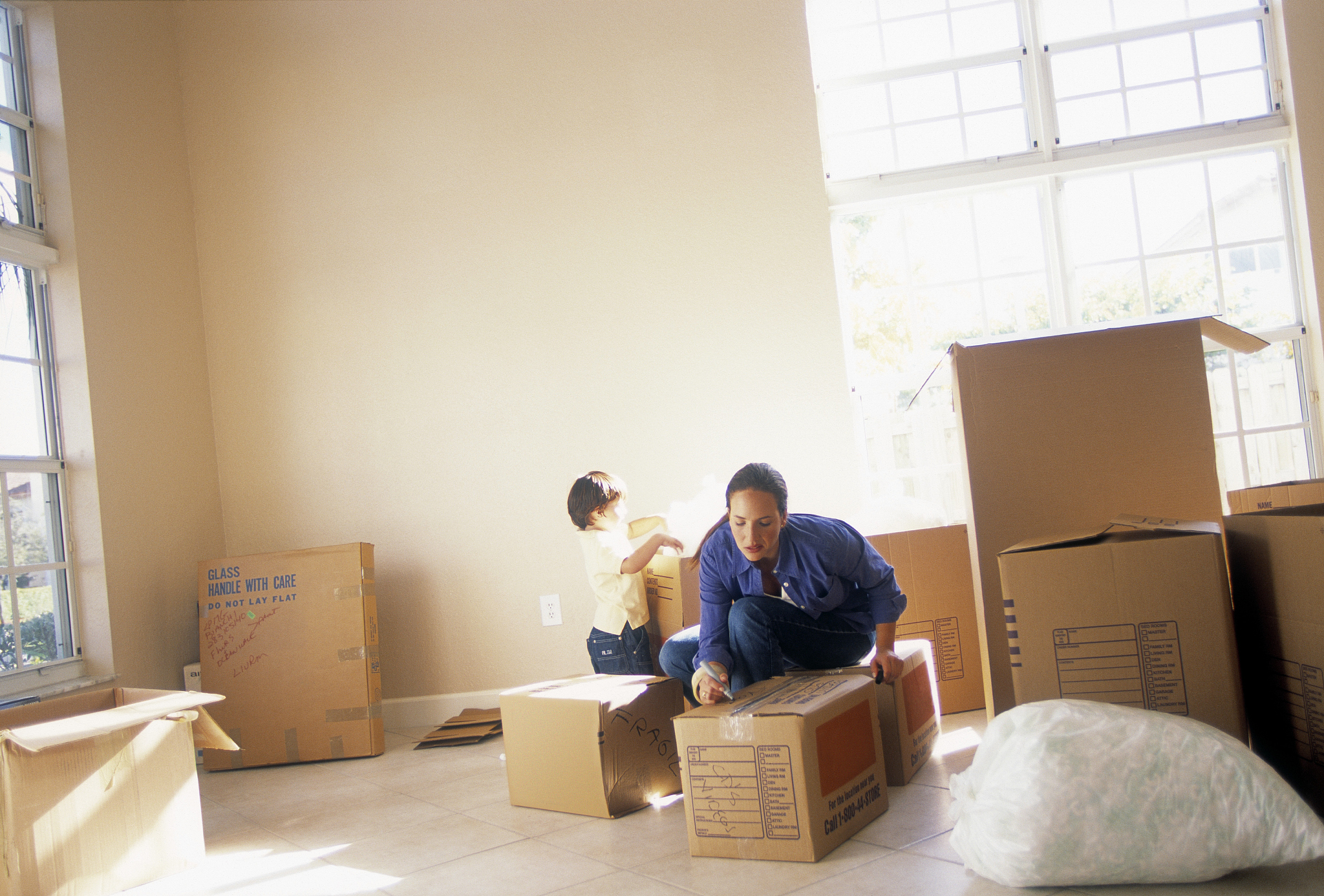 woman with young boy preparing boxes for moving