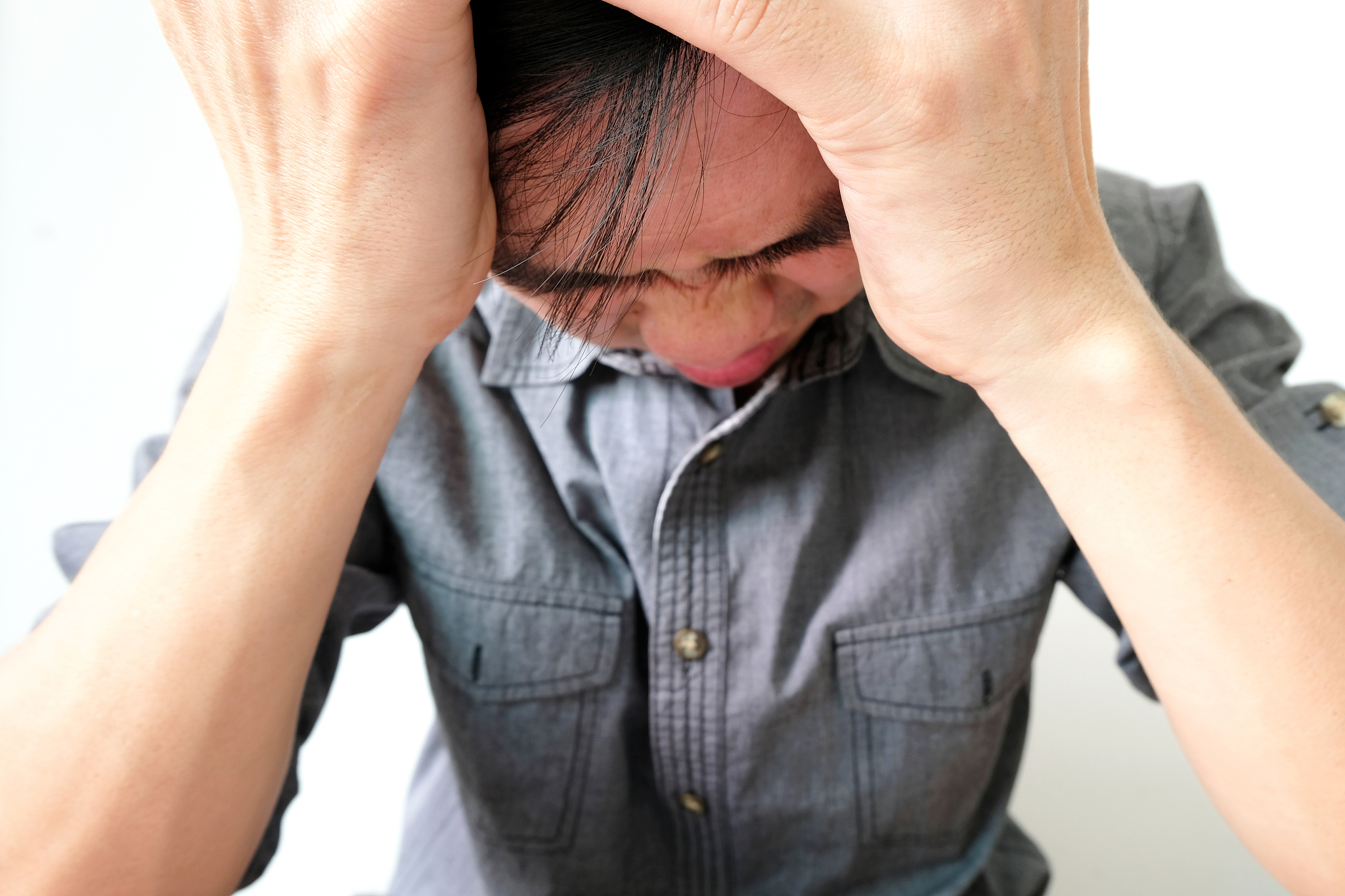 a man sitting down, his face unsettled.  he has headaches and st