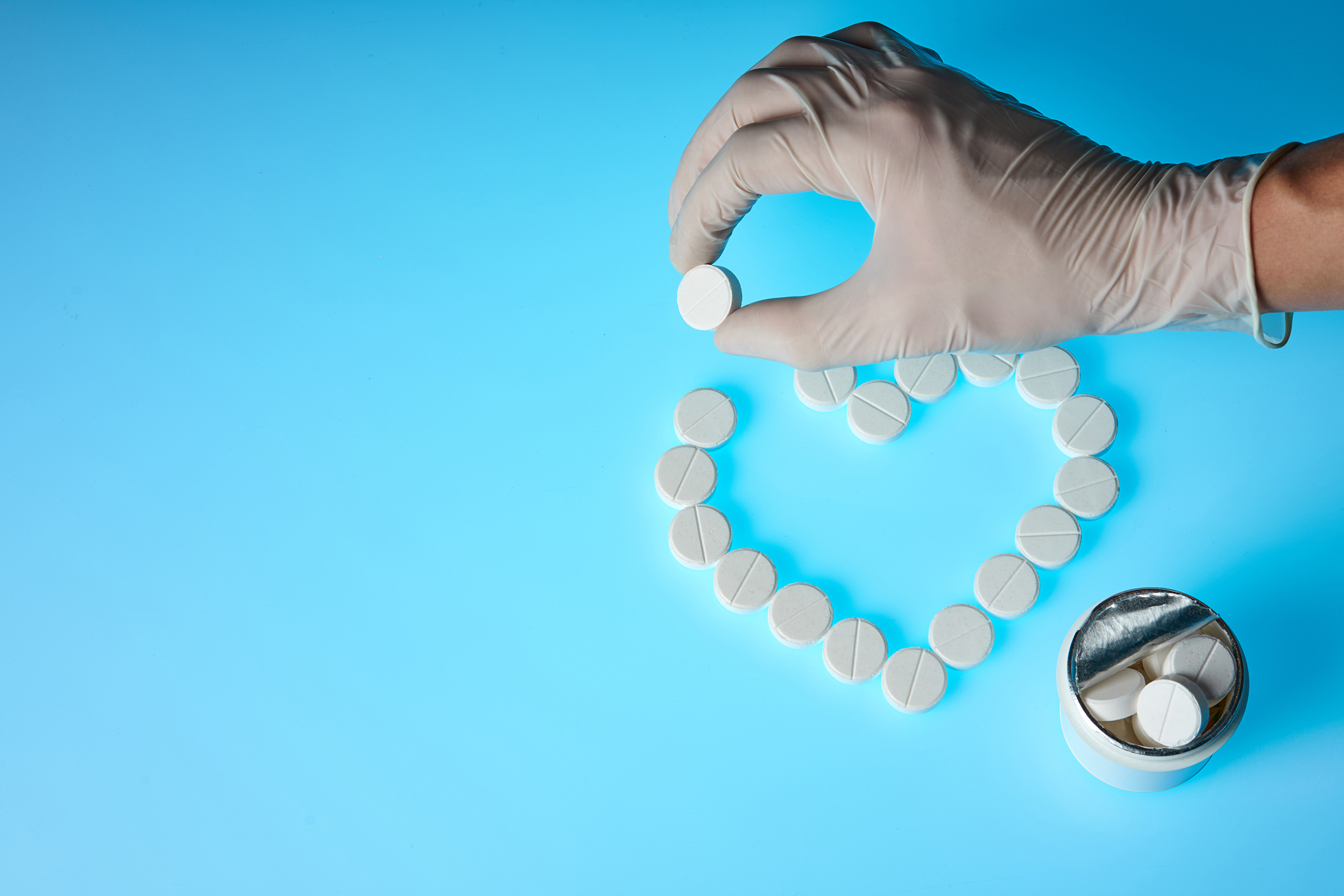 heart-shaped pills are on a blue background, and the doctor is h