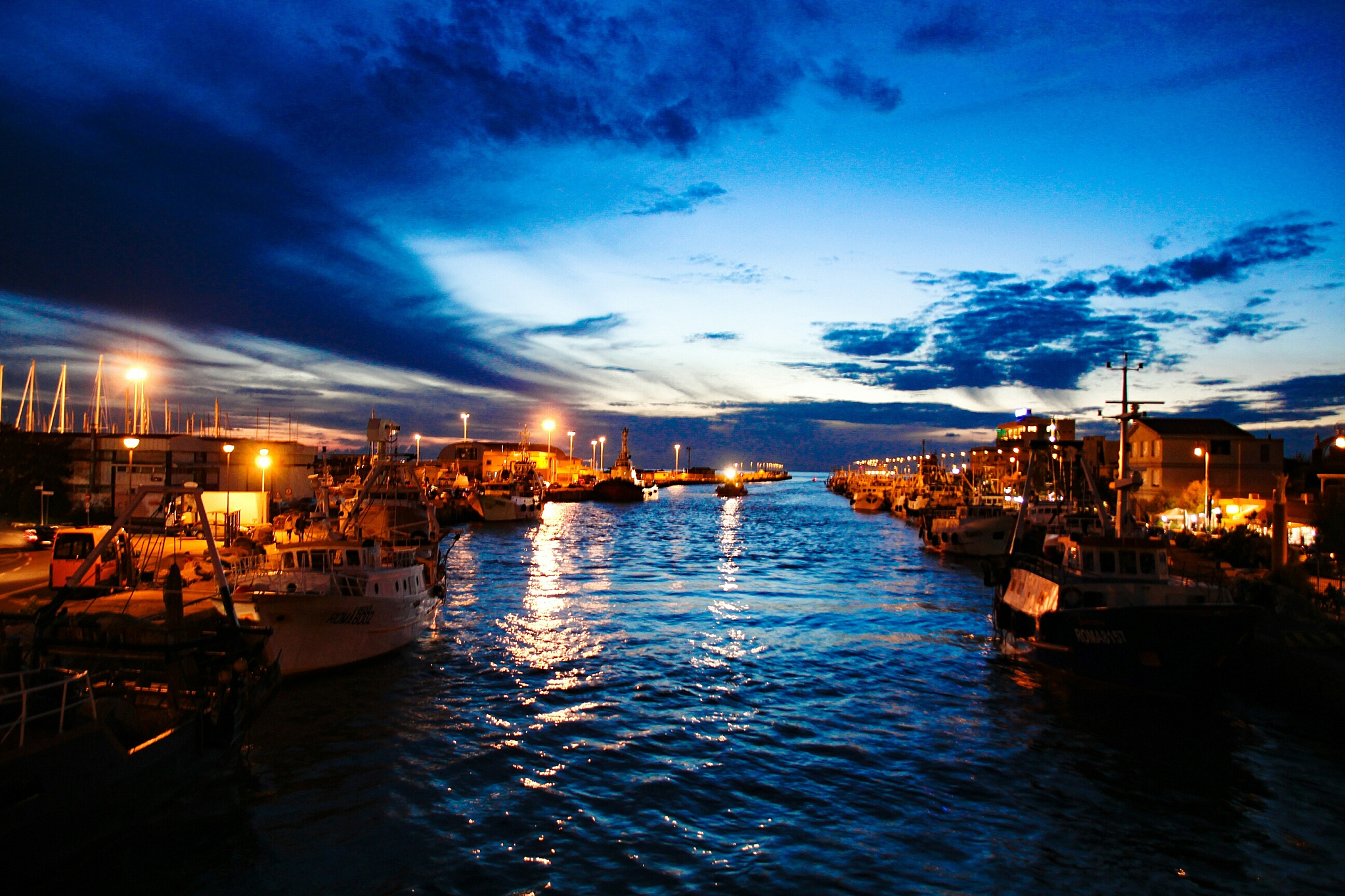 boats moored at harbor against sky at night