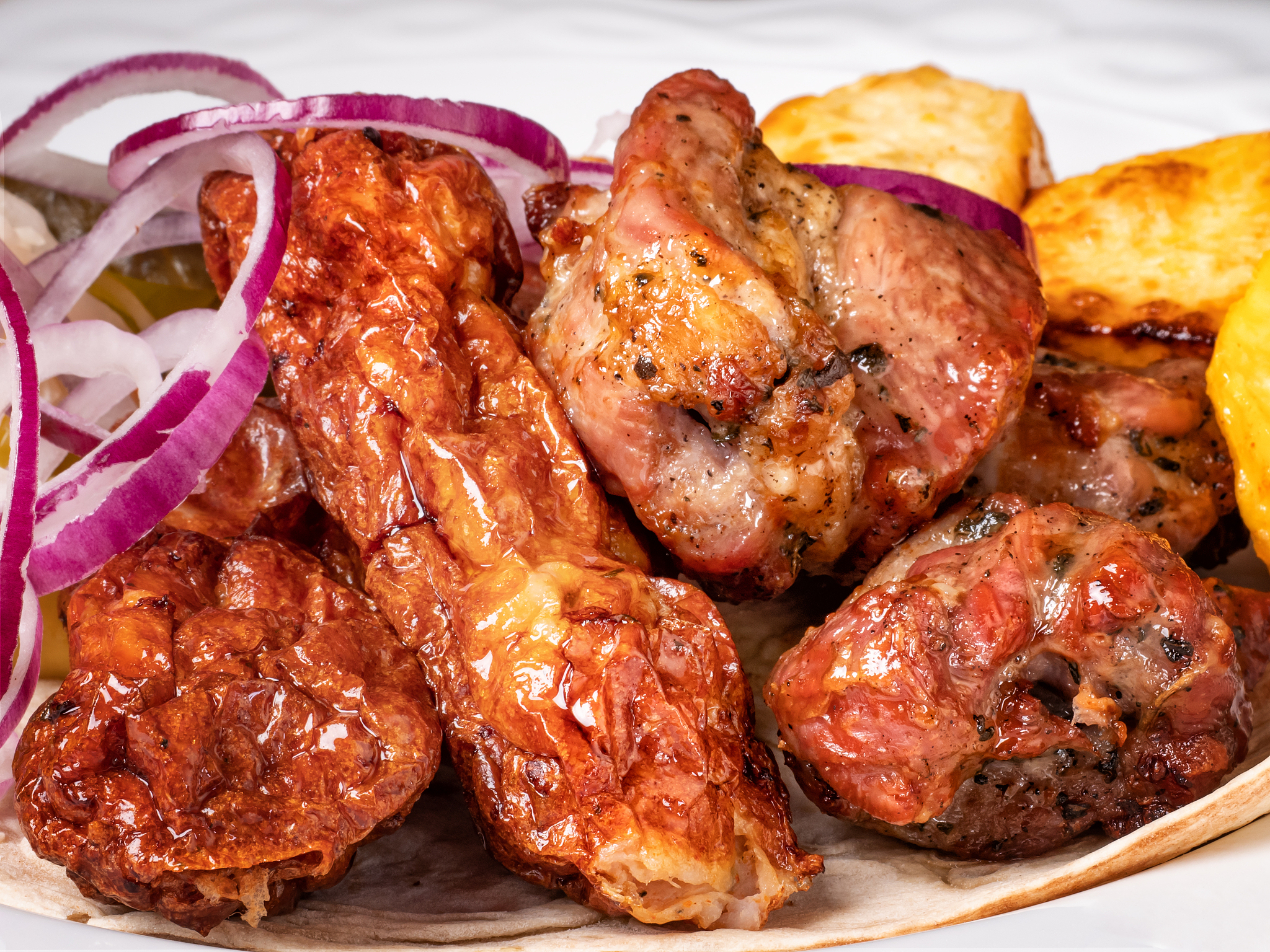 fried pieces of meat with fried potatoes and red onions.