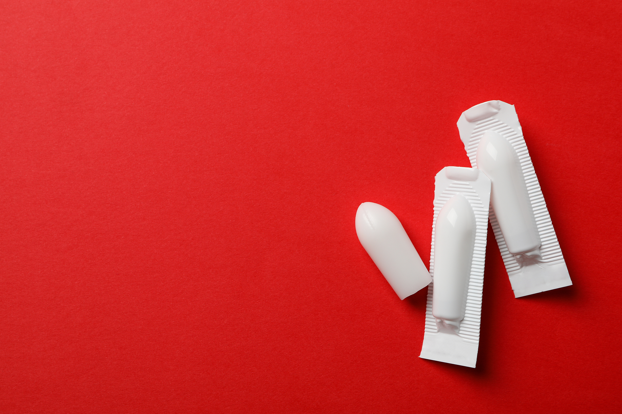 anal or vaginal candles on red background, top view