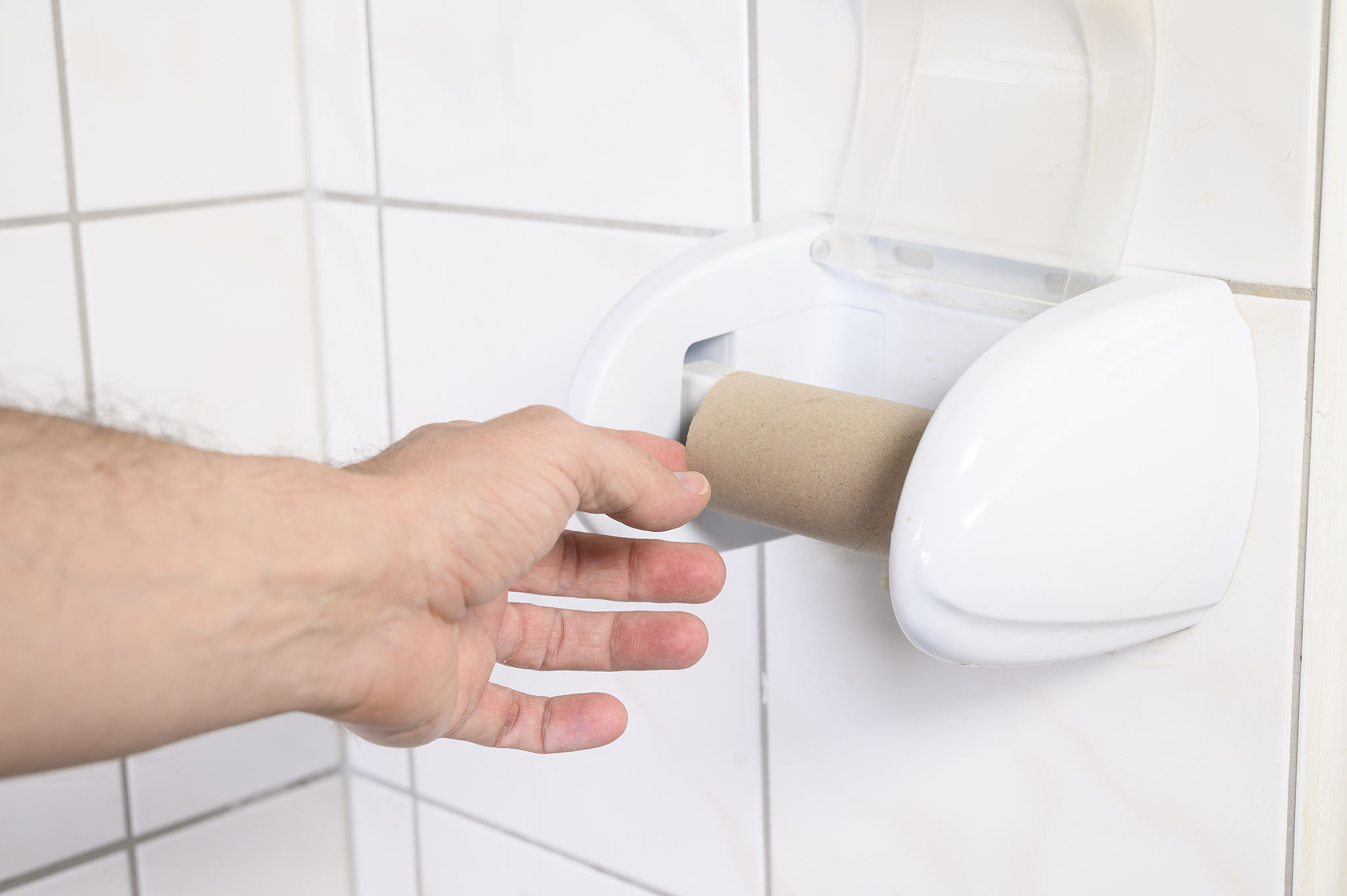 man's hand taking an empty toilet paper in a wc.