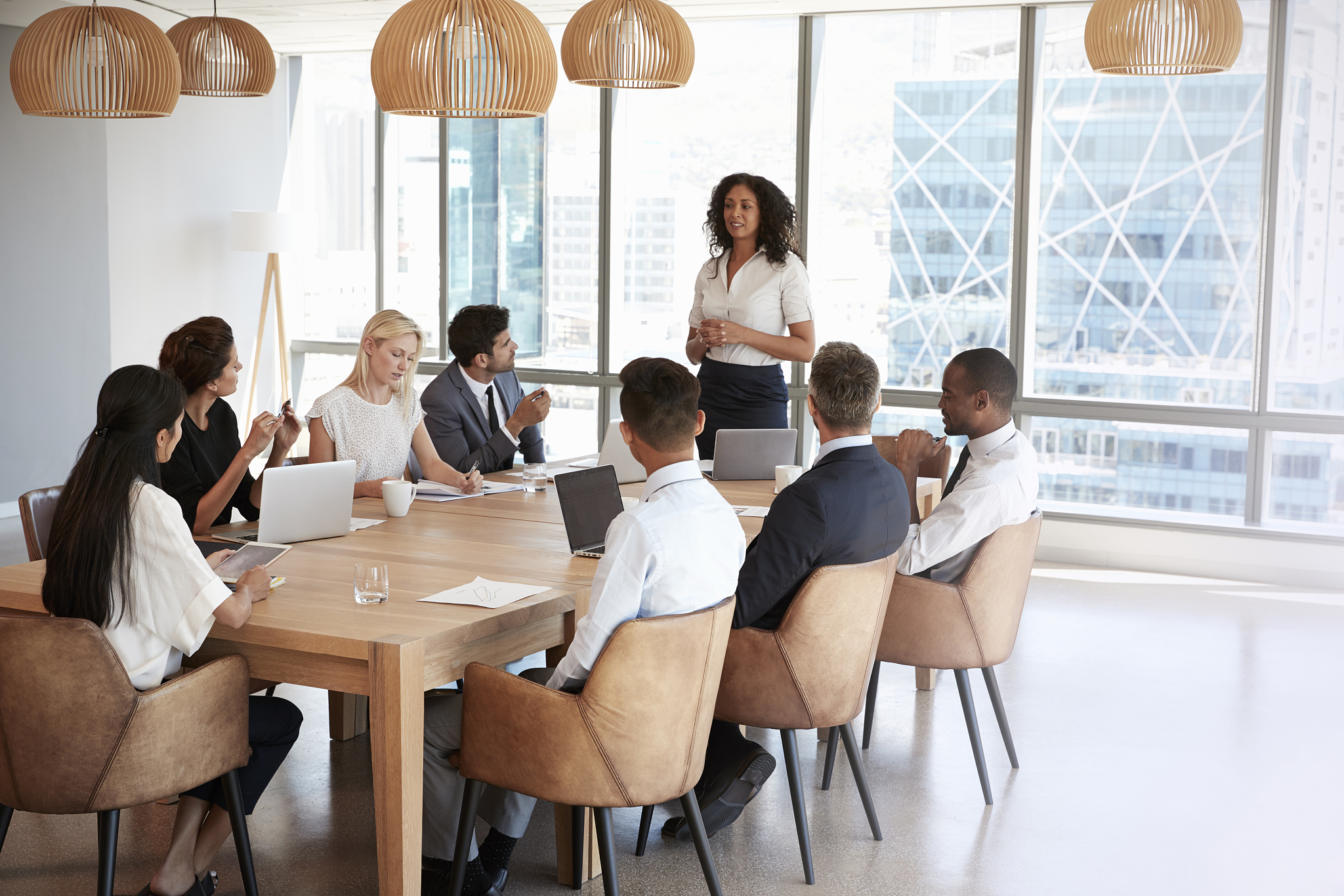 businesswoman stands to address meeting around board table