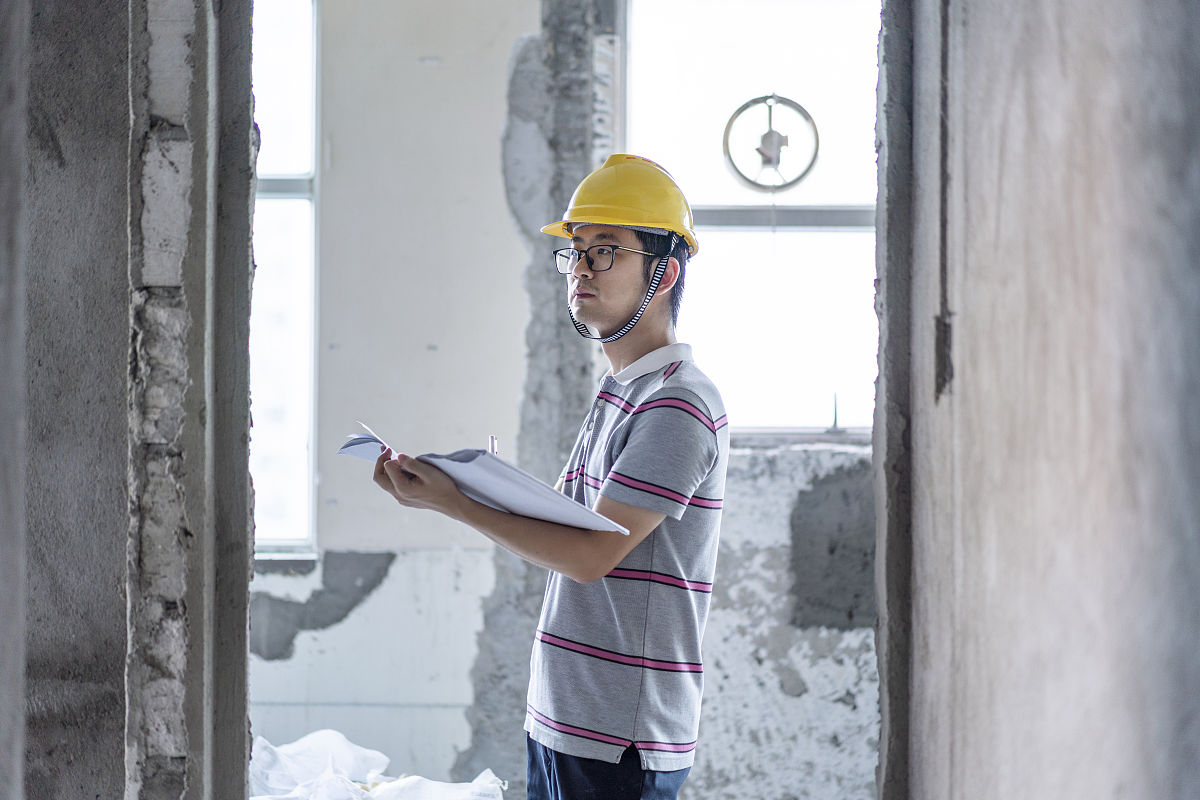 亚洲男性工程师在装修工地施工图纸