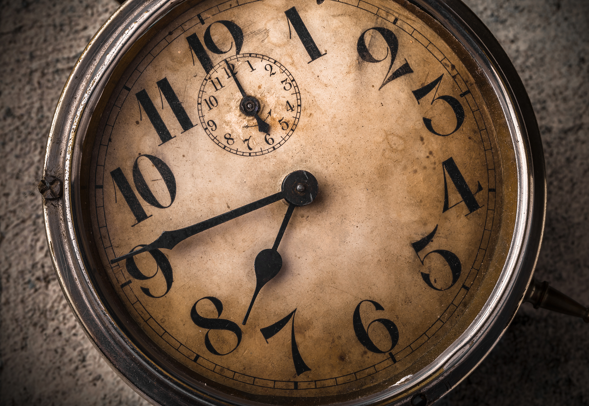 old rustic metal clock close up on textured concrete background