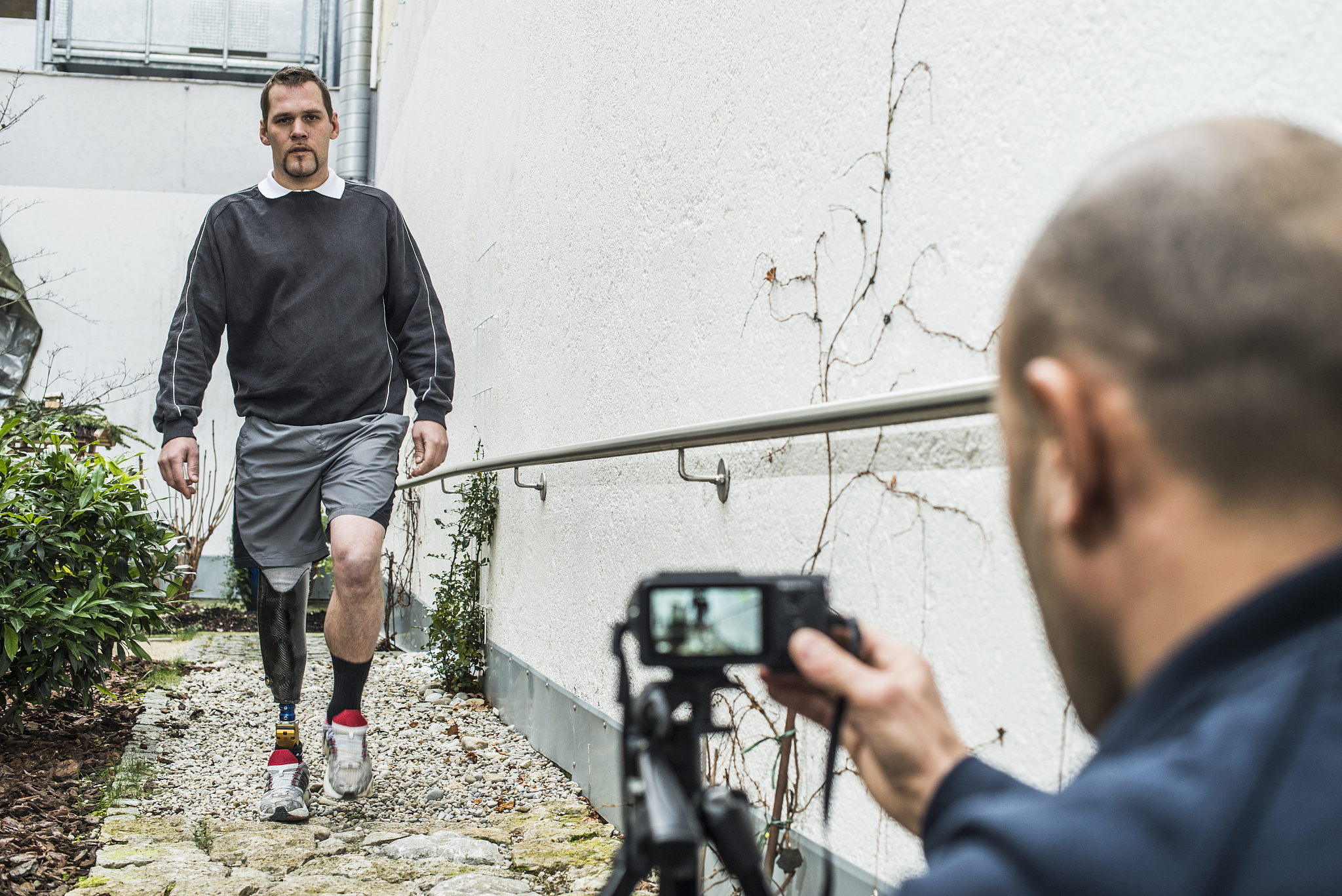 physical therapist filming man with prosthetic leg