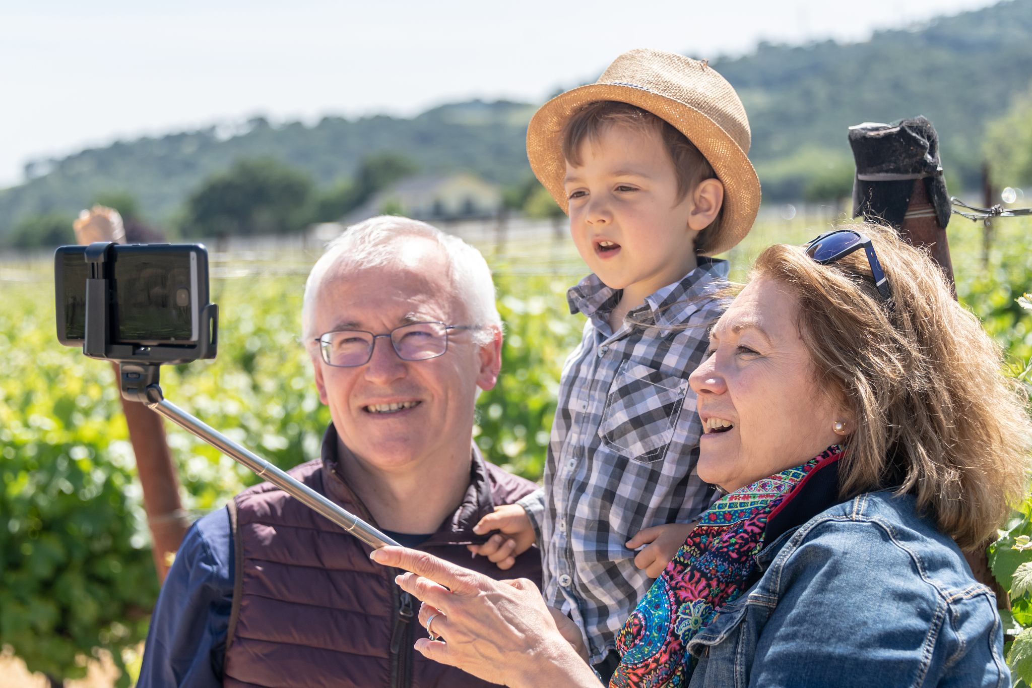 senior couple and their grandson taking a selfie at the vineyard