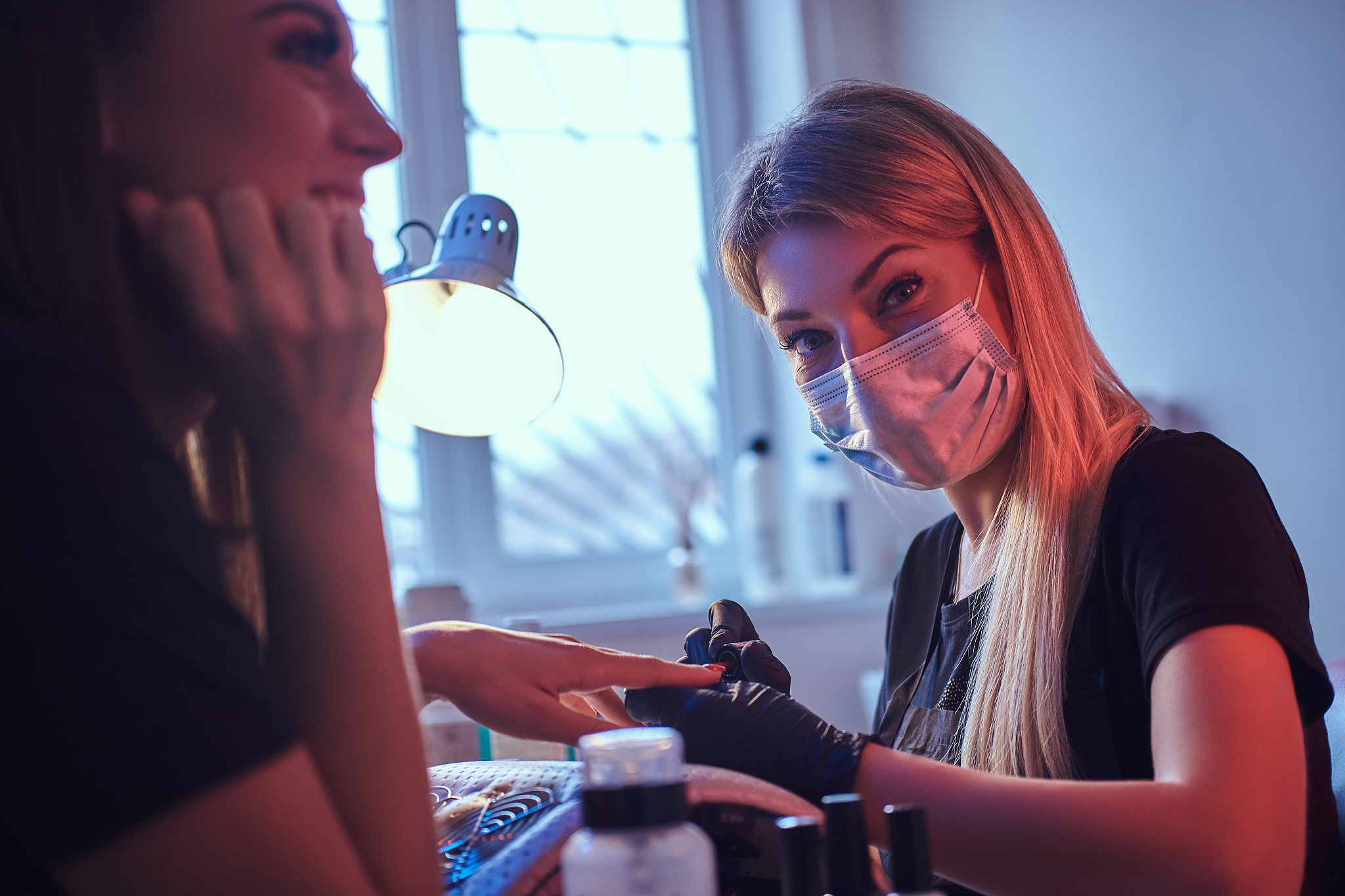 master manicure looking at a camera while working with client's 