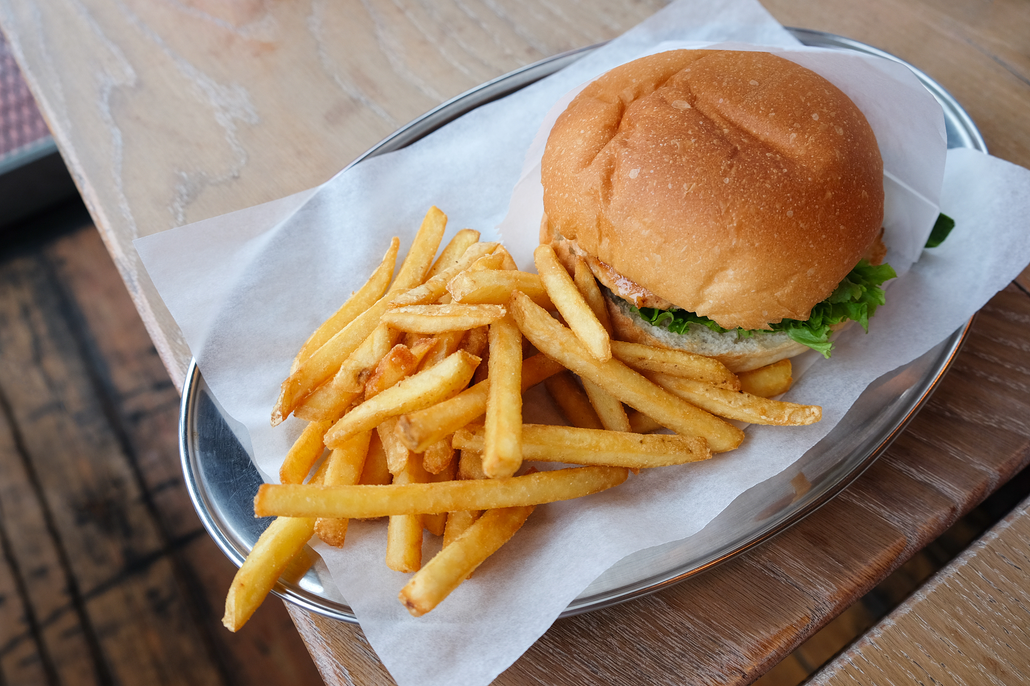 burger and french fries on parchment paper, on tin dish, on wood