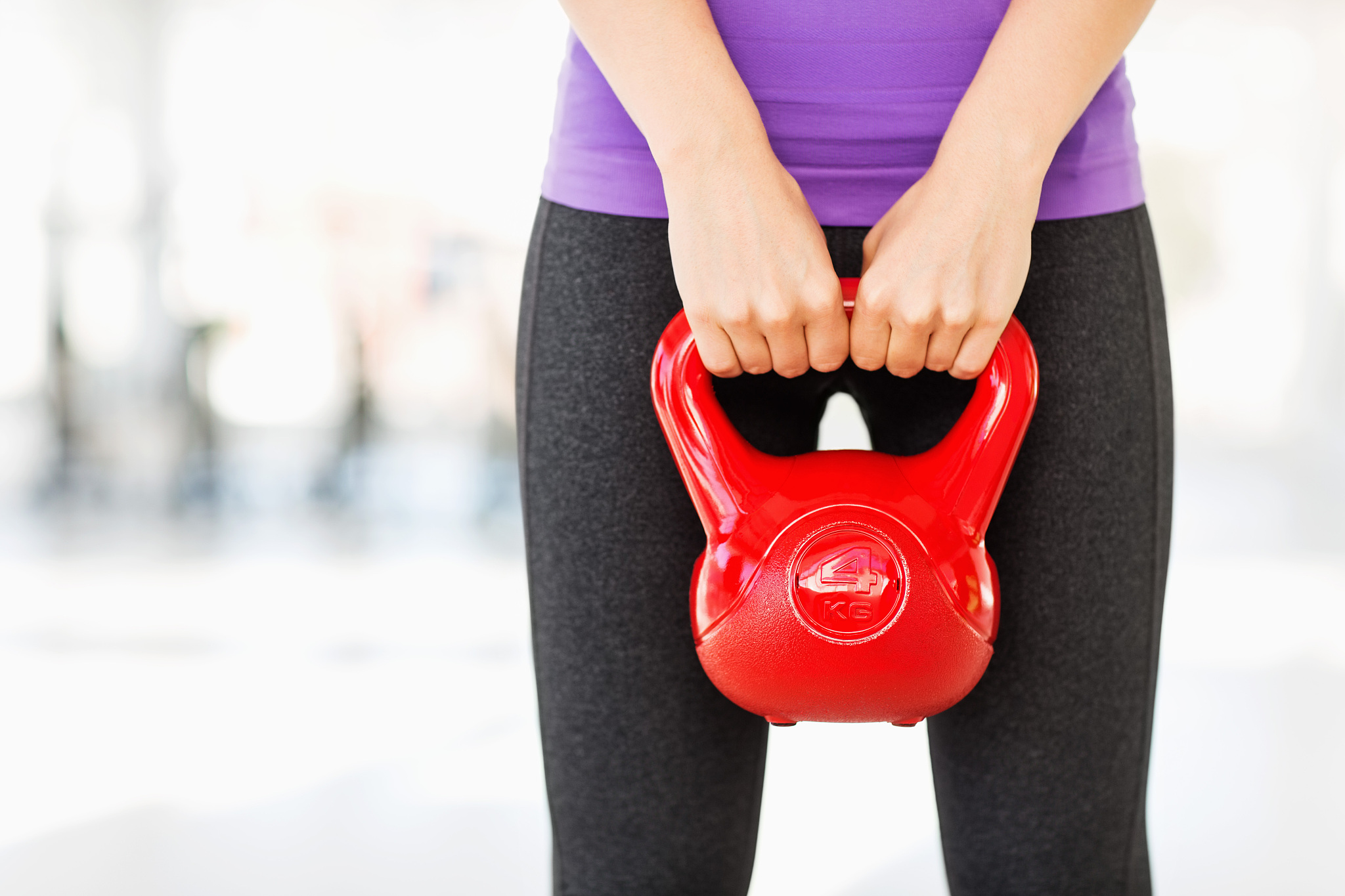 woman lifting kettle bell while exercising in gym