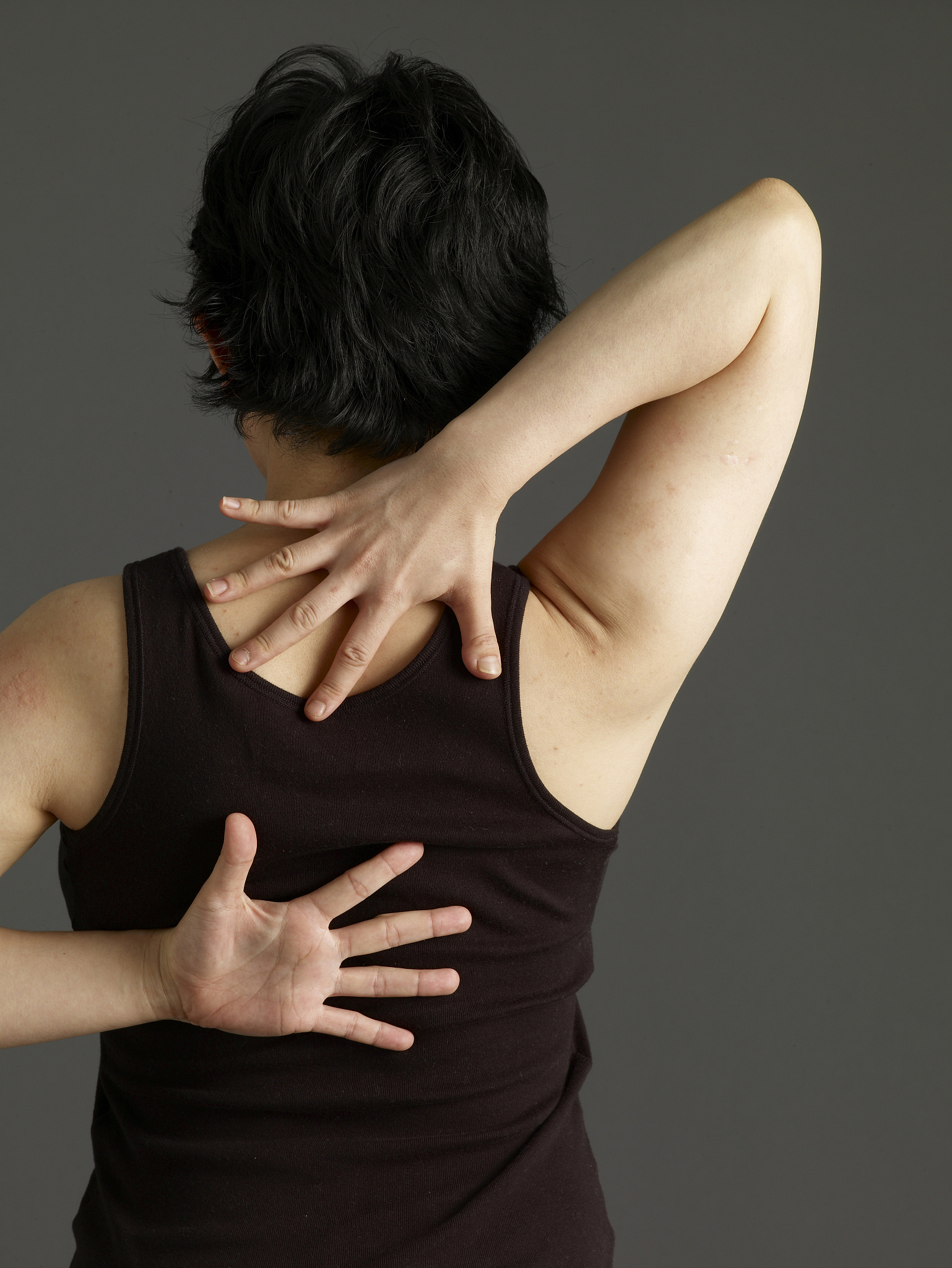 woman with hands behind her back, stretching, rear view