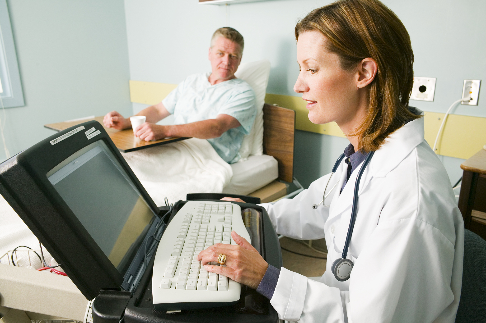 doctor using laptop in patient's hospital room