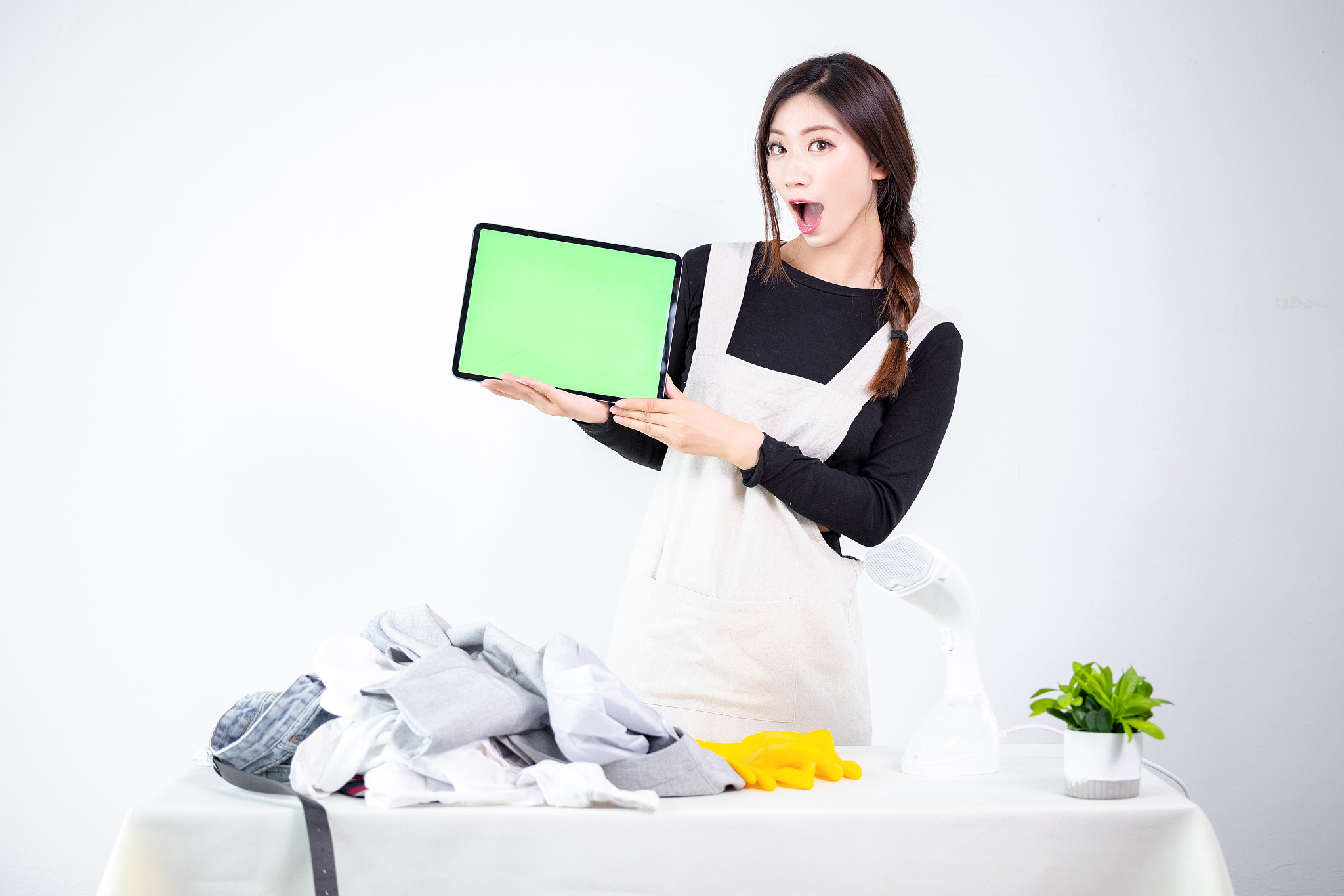 烫衣服的亚洲女性,拿着平板电脑做展示