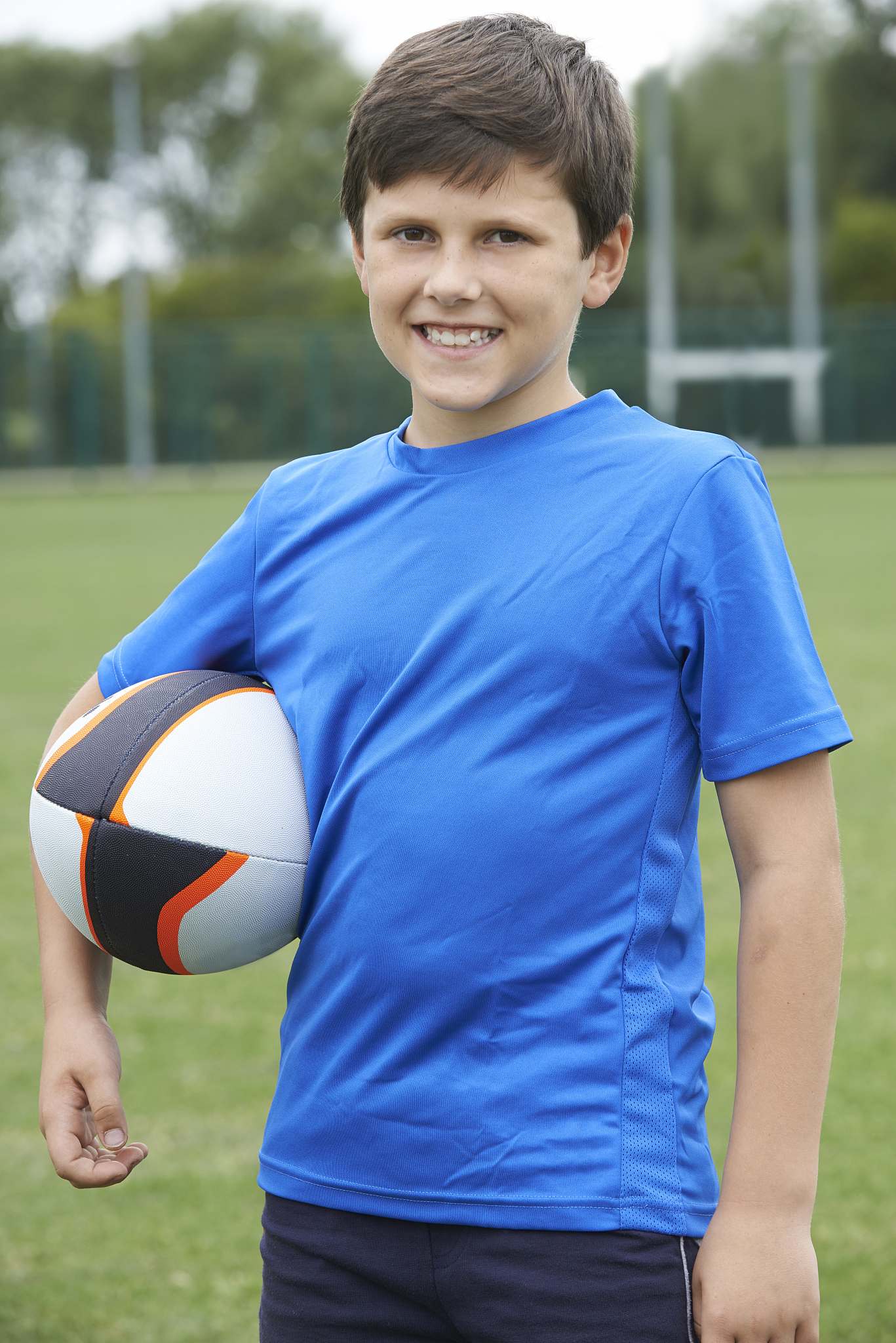portrait of boy holding ball on school rugby pitch