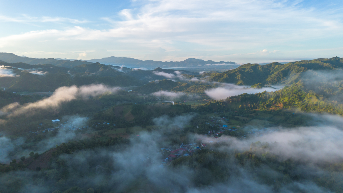 请用100字形容一下房子后远山云雾环绕的场景