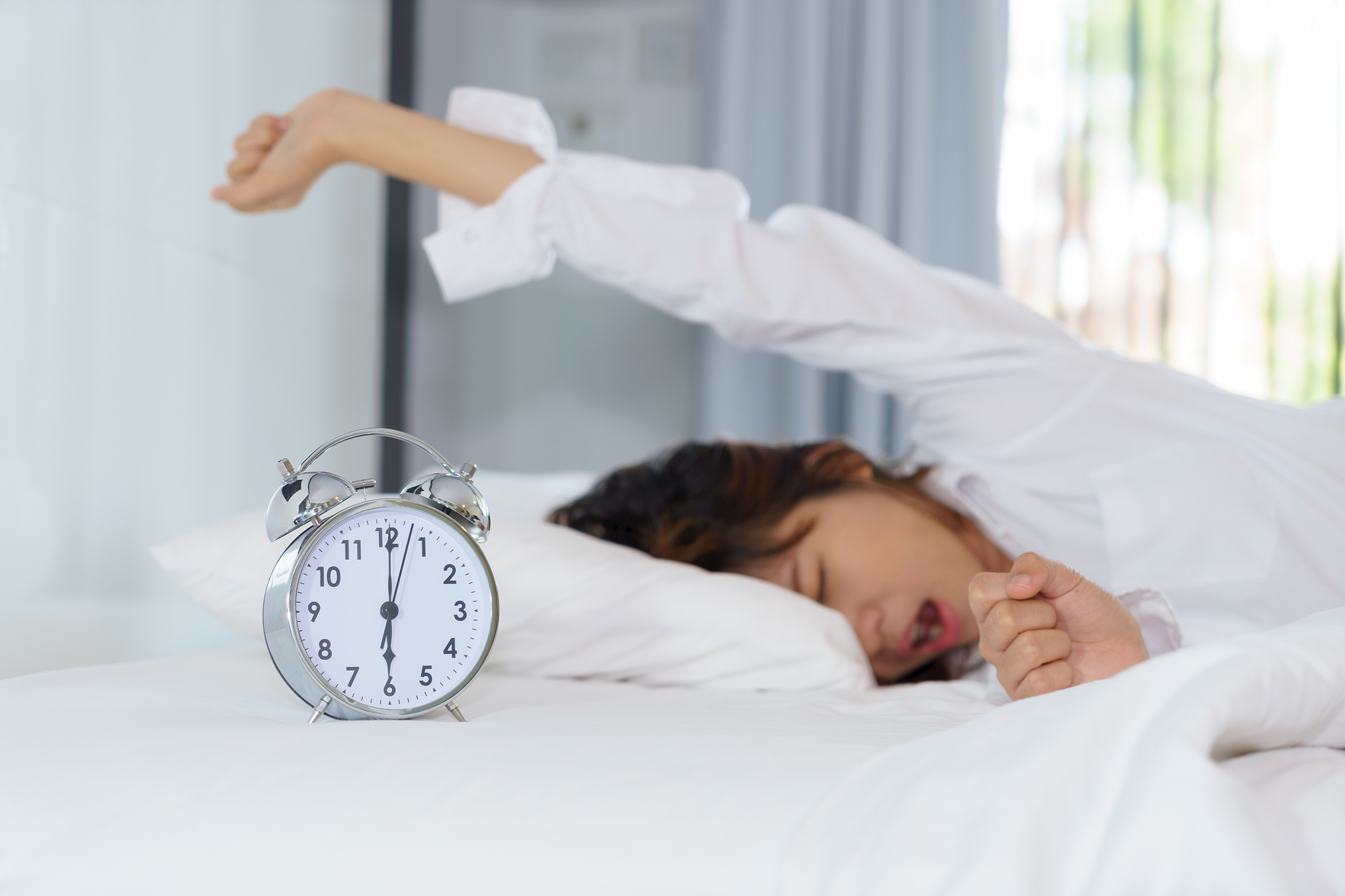 woman yawning while lying on bed at home