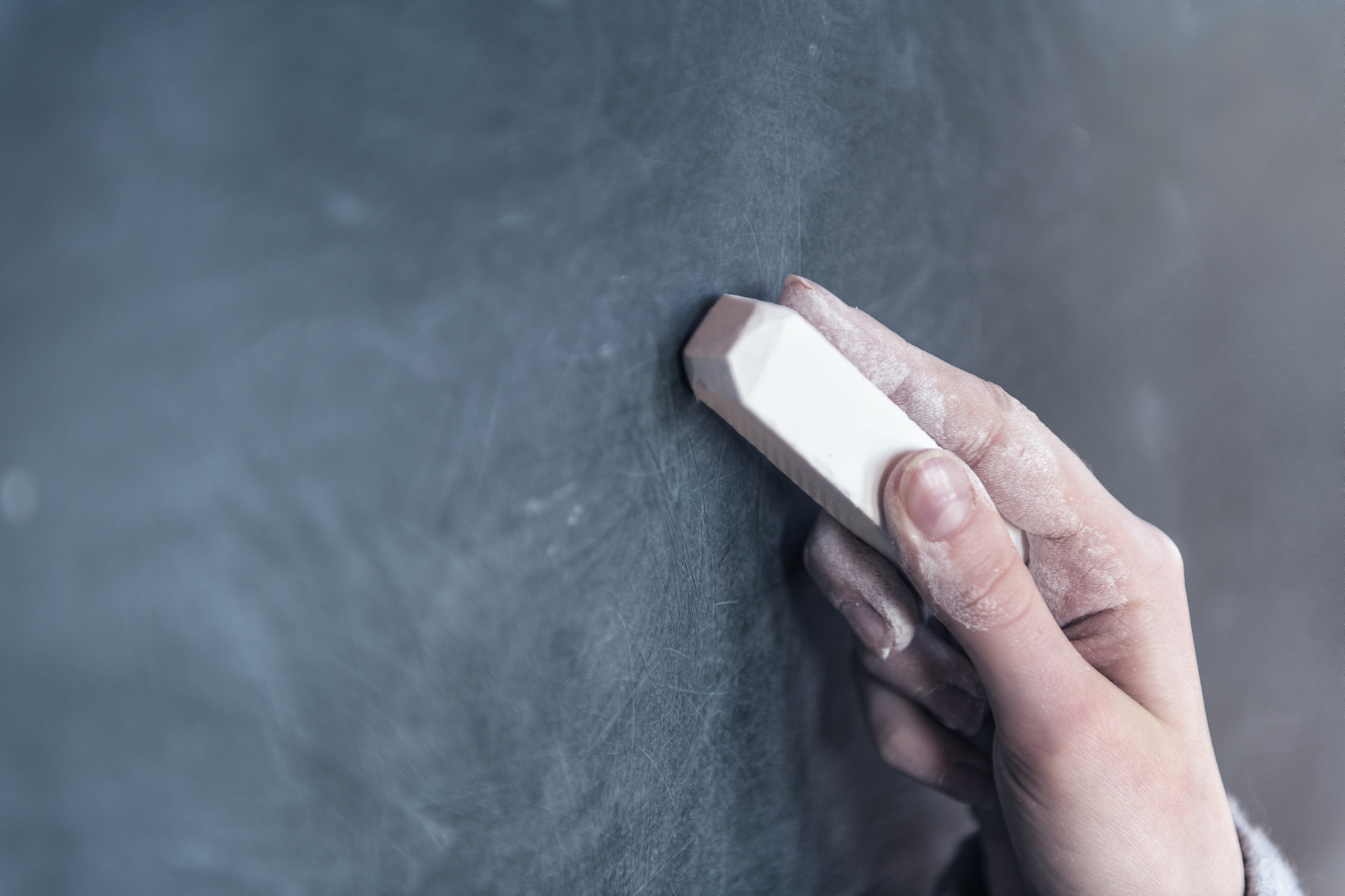 cropped hand writing on blackboard in classroom