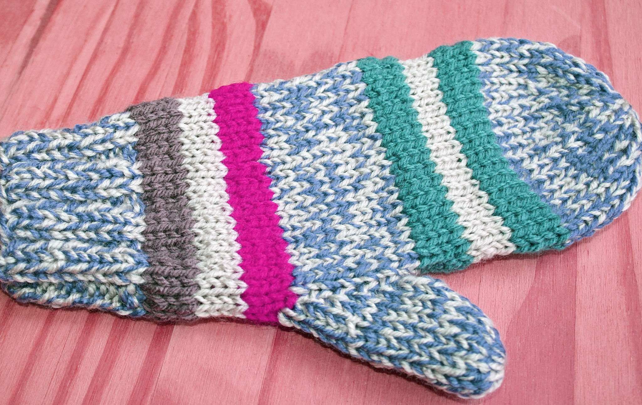 bright and colorful handmade knitted mitten in blue, white, pink