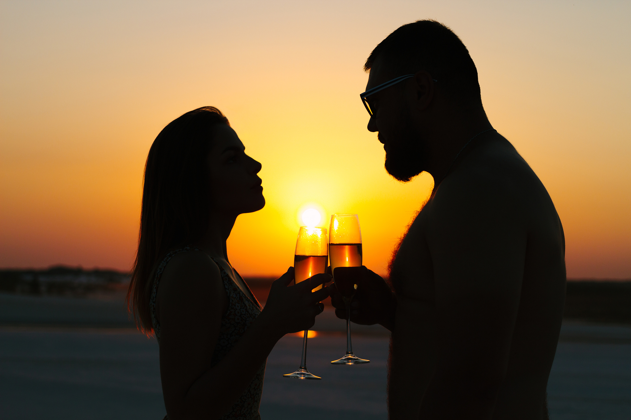 silhouettes of man and woman, happy couple in love on the beach 