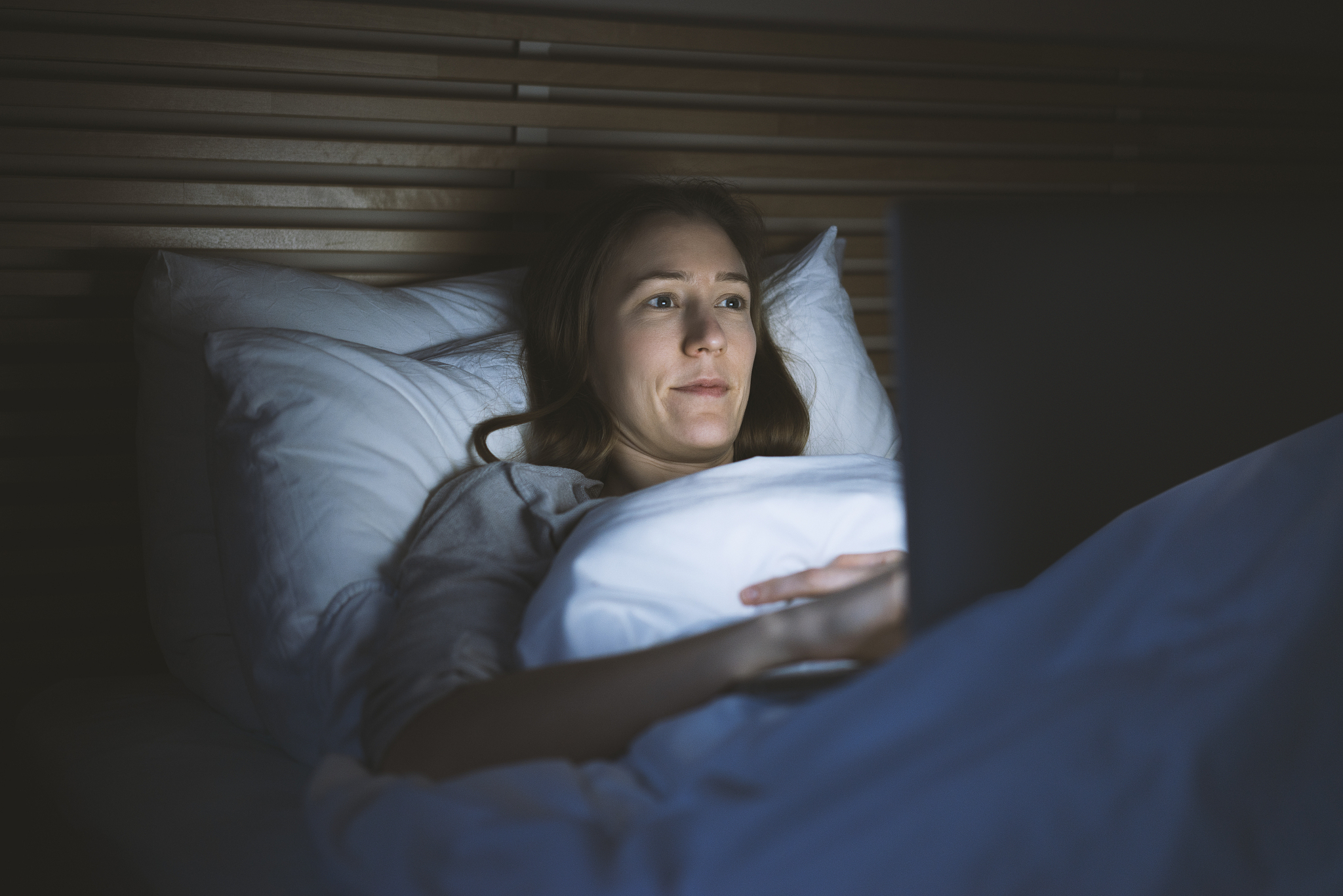woman using laptop in bed at night