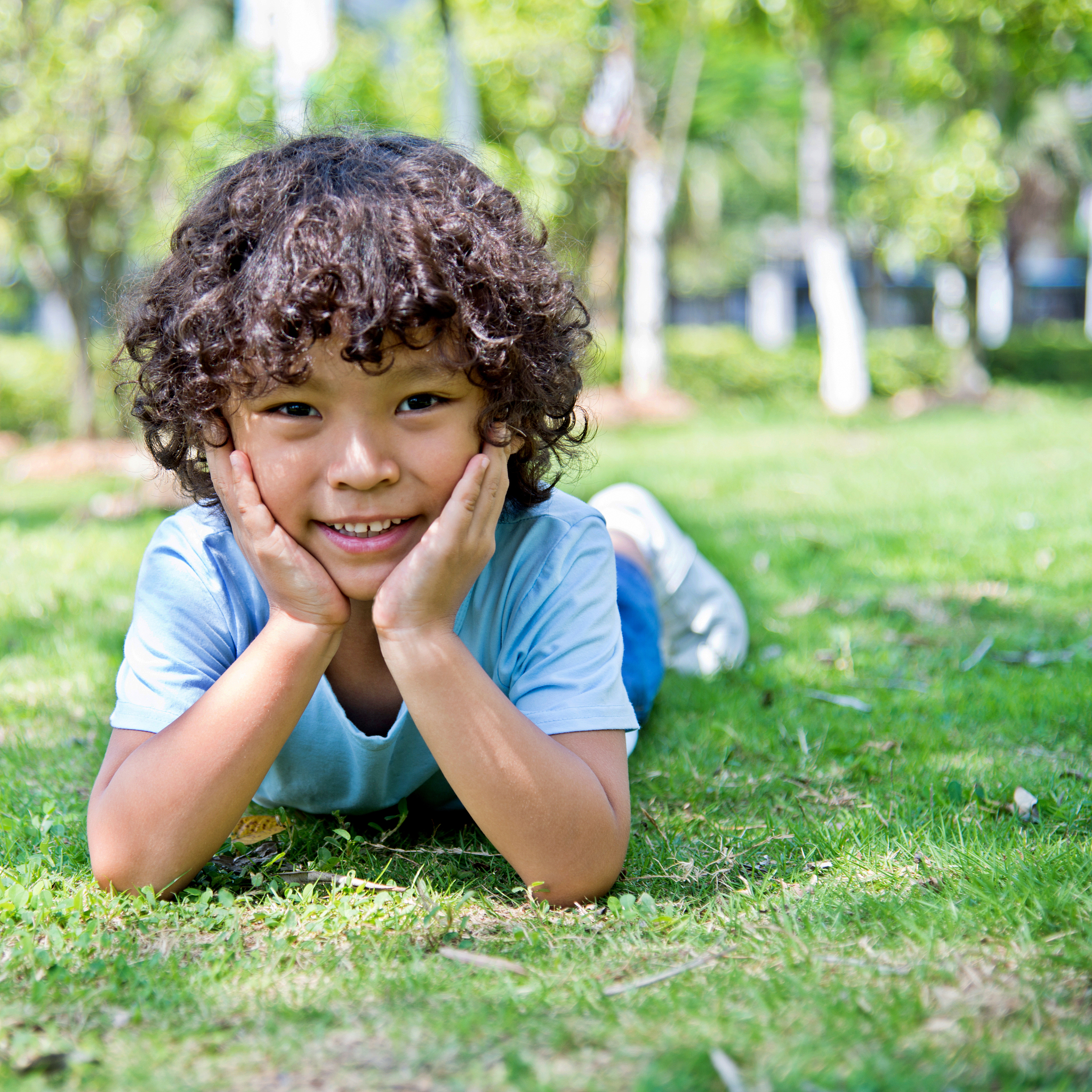 young asian boy lying on grass