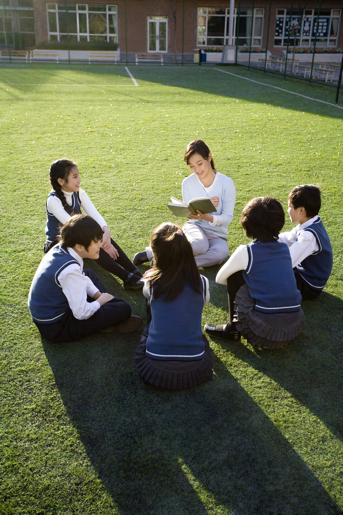 小学生在草地上围着老师学习