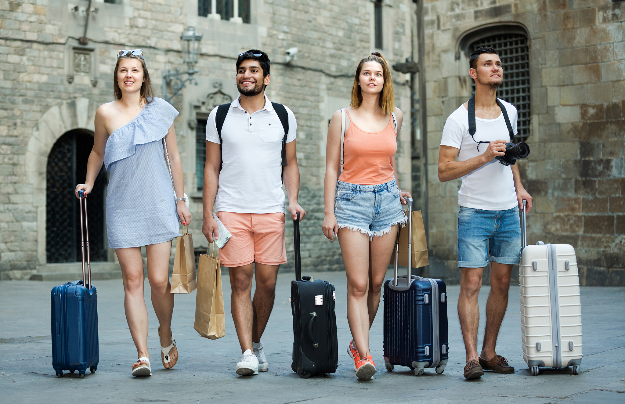 two men and women are walking together with luggage