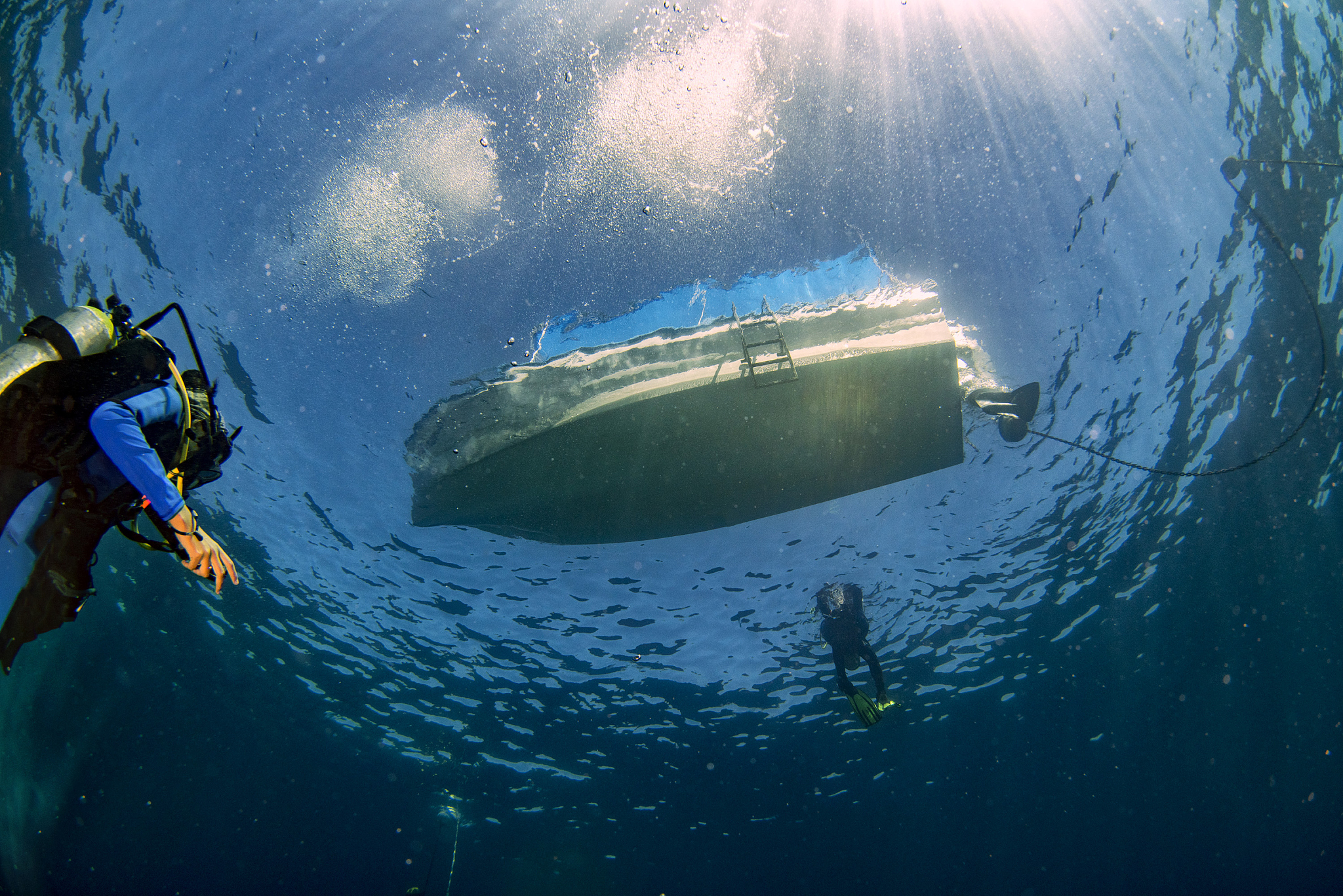 boat ship from underwater blue ocean with sun rays