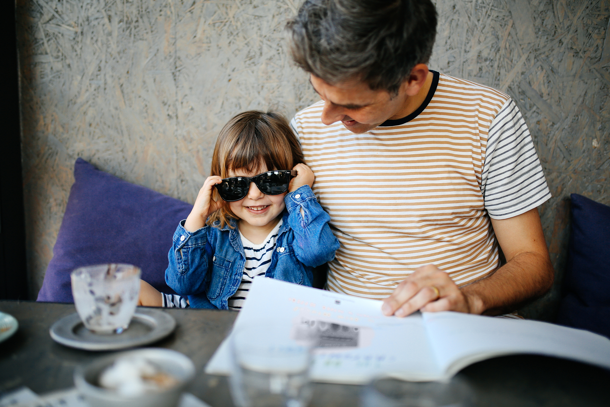 girl playing with fathers sunglasses in cafe