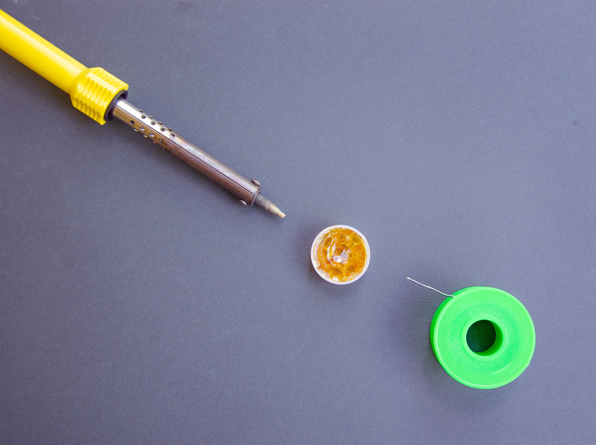 soldering iron, tin, rosin on a yellow background. macro. repair