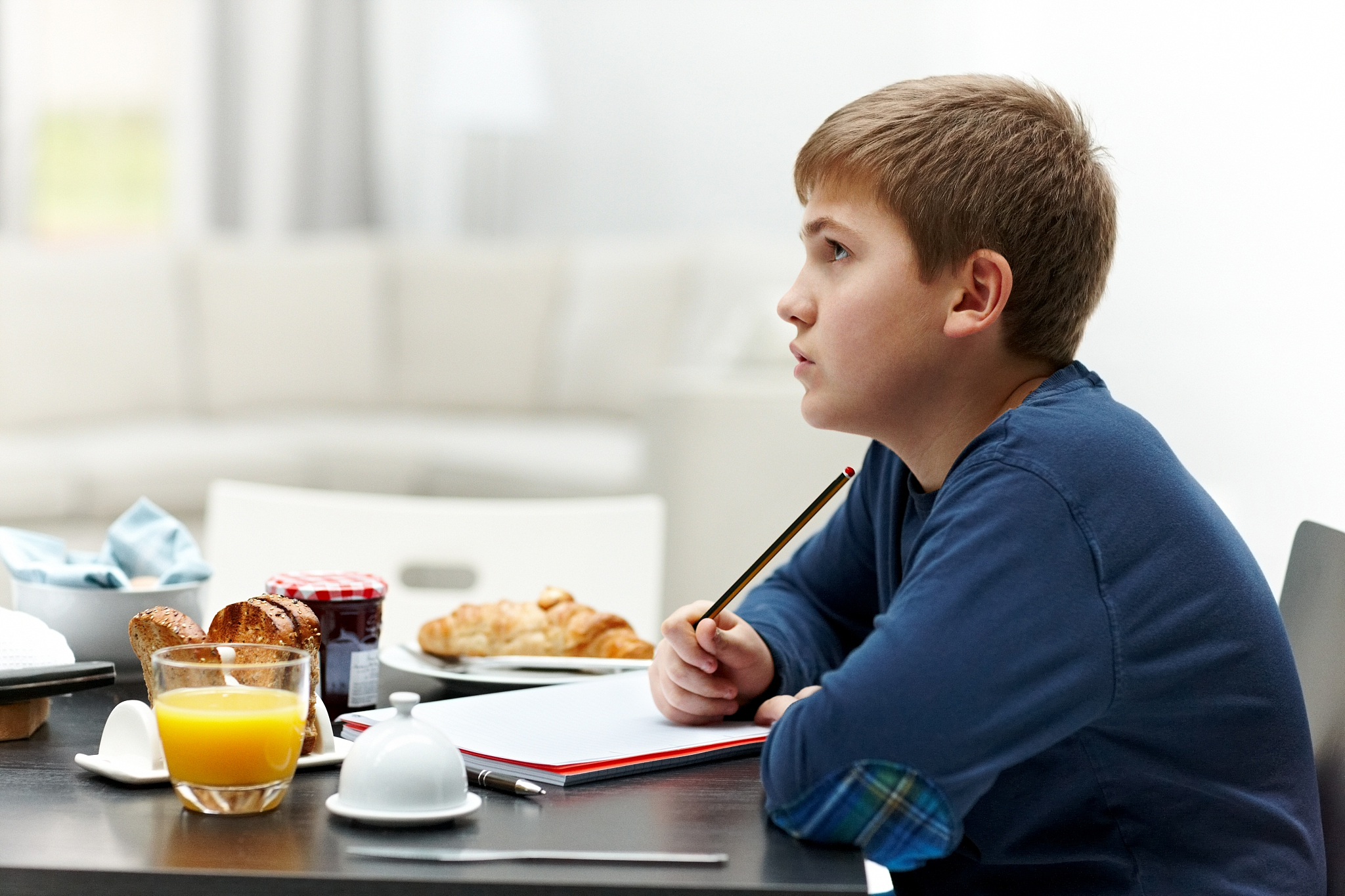 young boy doing school work at breakfast table
