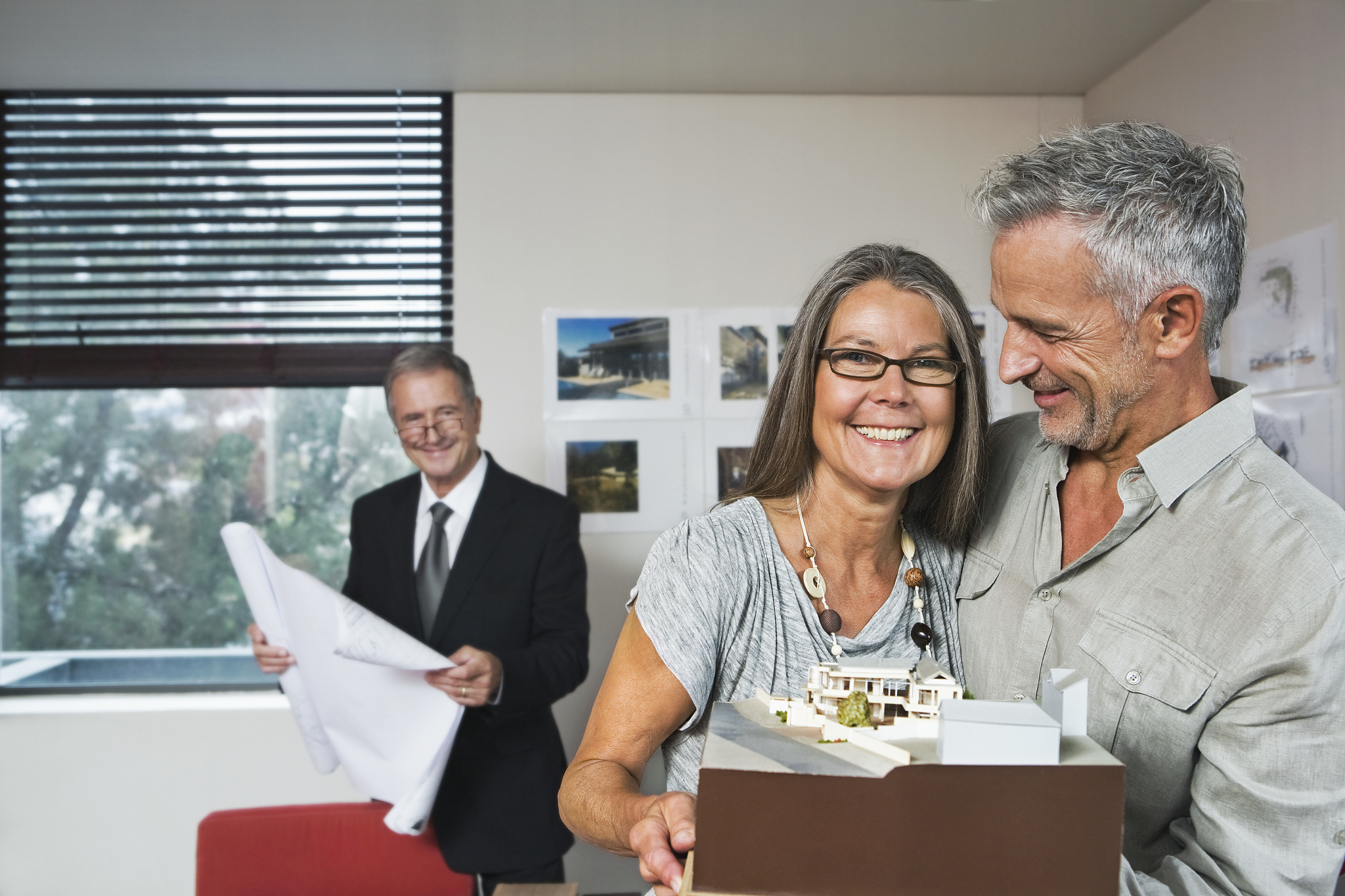 proud middle aged couple holding architectural model of new home