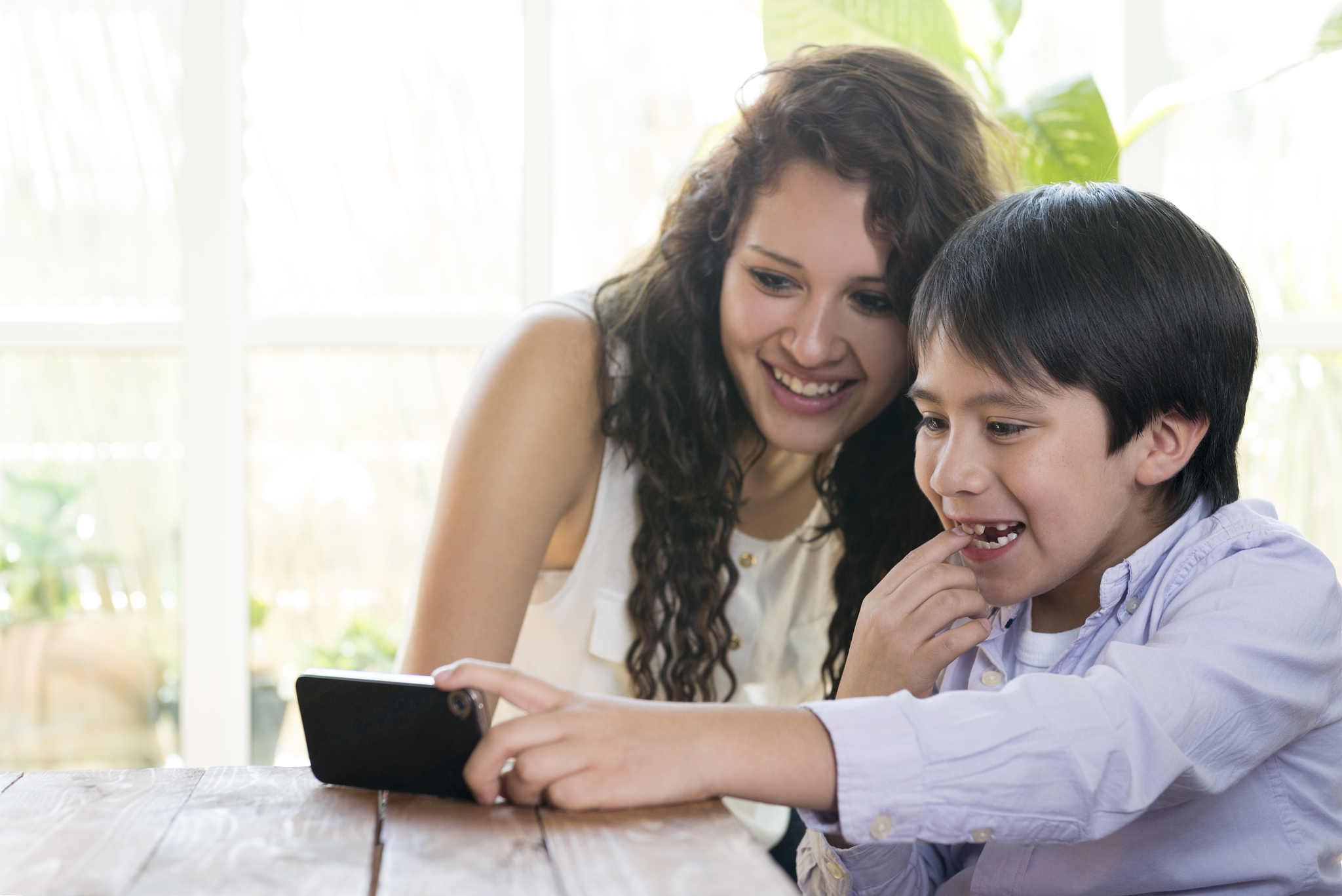 young woman and boy watching movie on cellphone