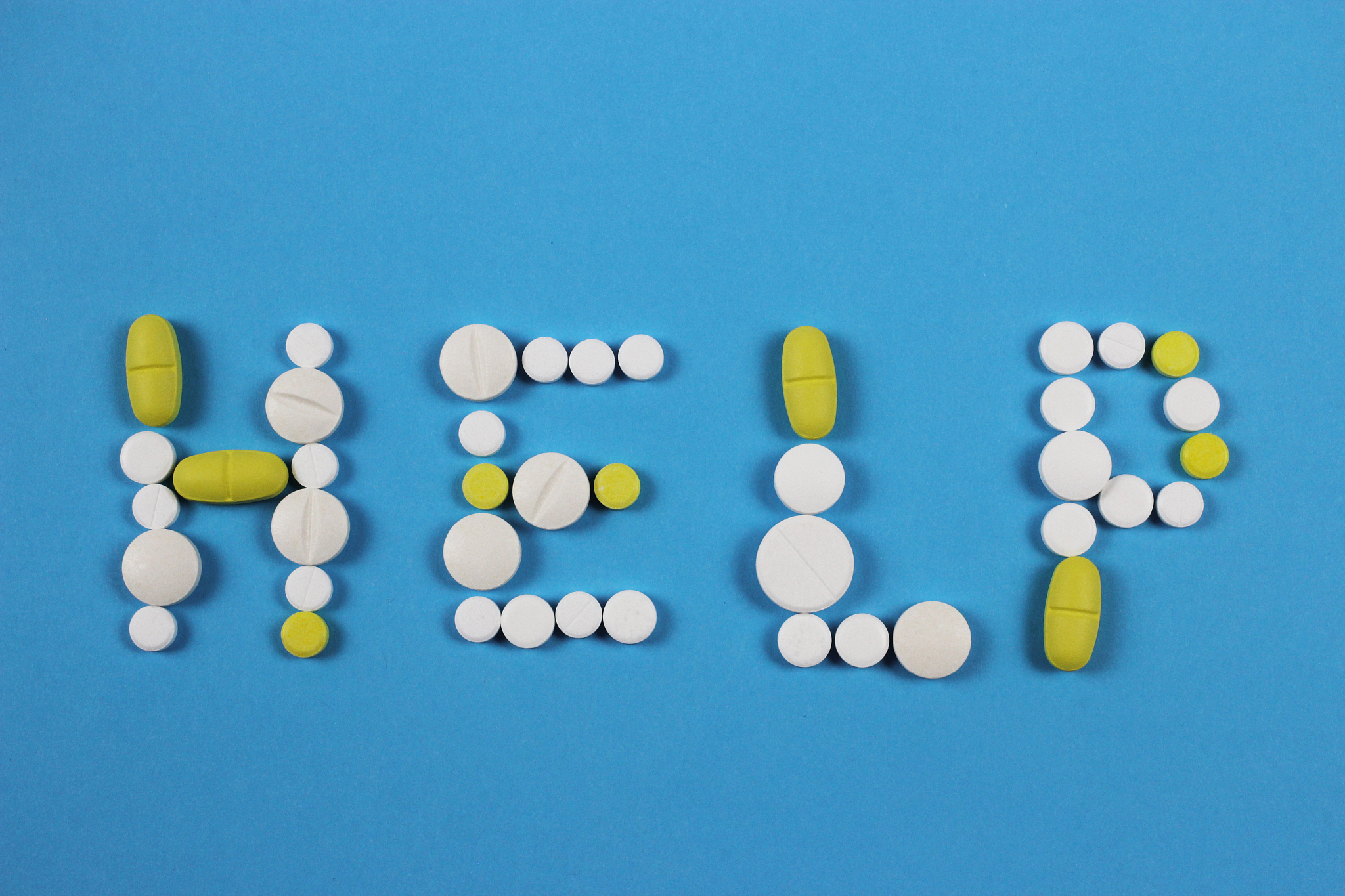 word help made by white and yellow pills on blue background