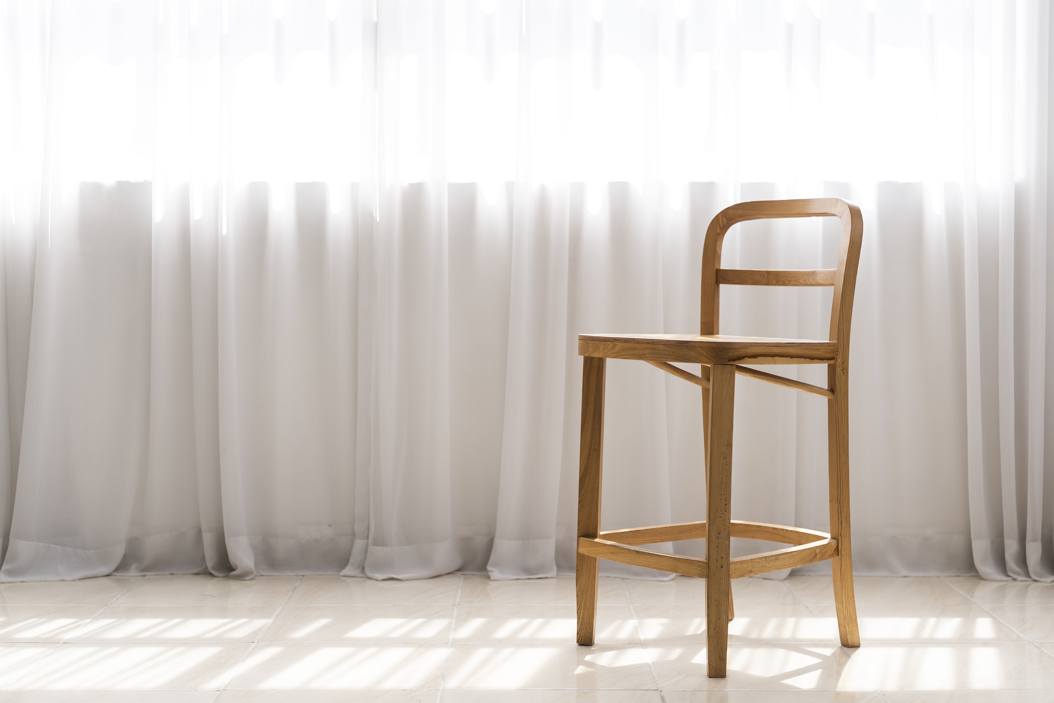 photography of wooden chair by the curtain and lights through wi