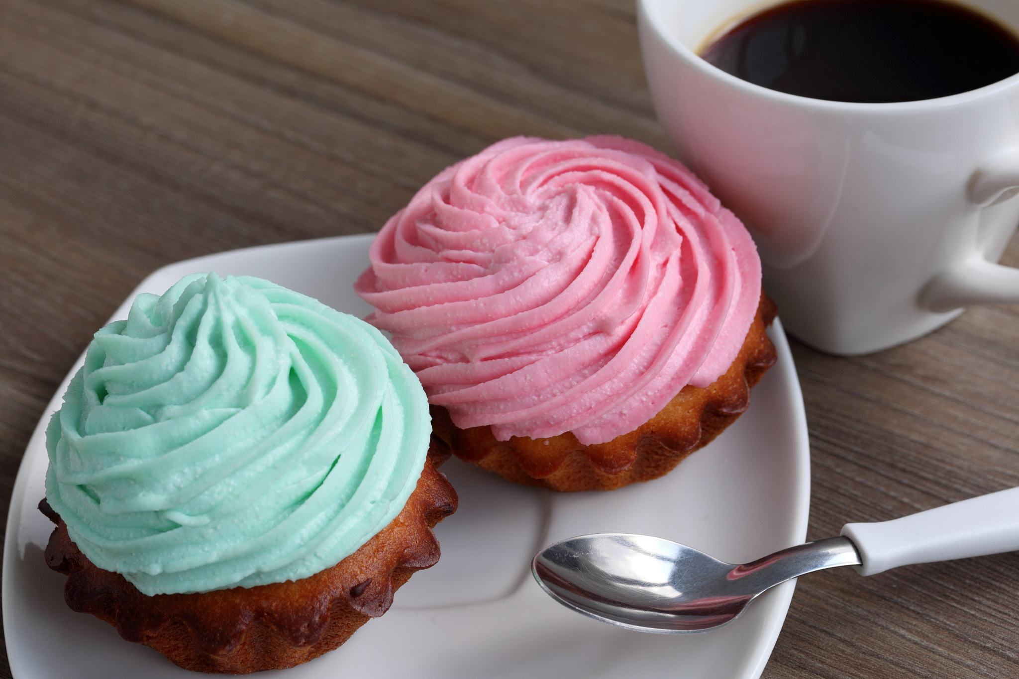 two cream cakes and a cup of coffee. cakes lie on a saucer. near