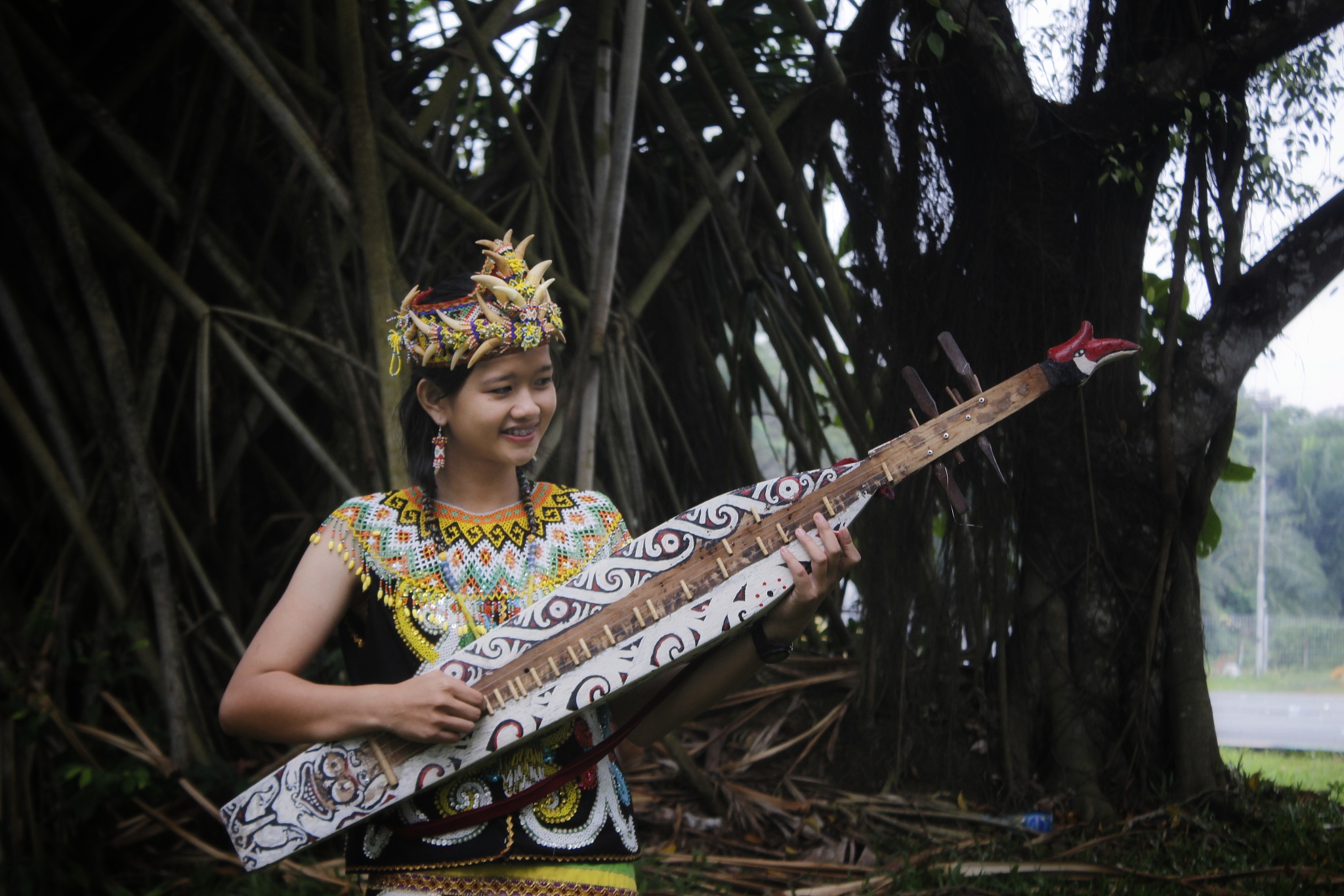 smiling woman playing traditional musical instrument against tre
