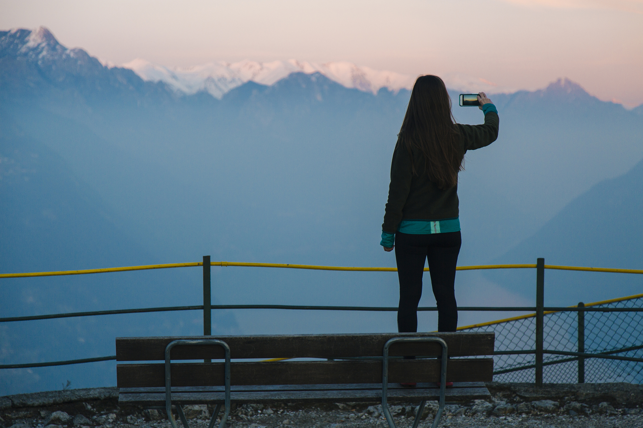 woman takes smart phone pic of mountains and lake